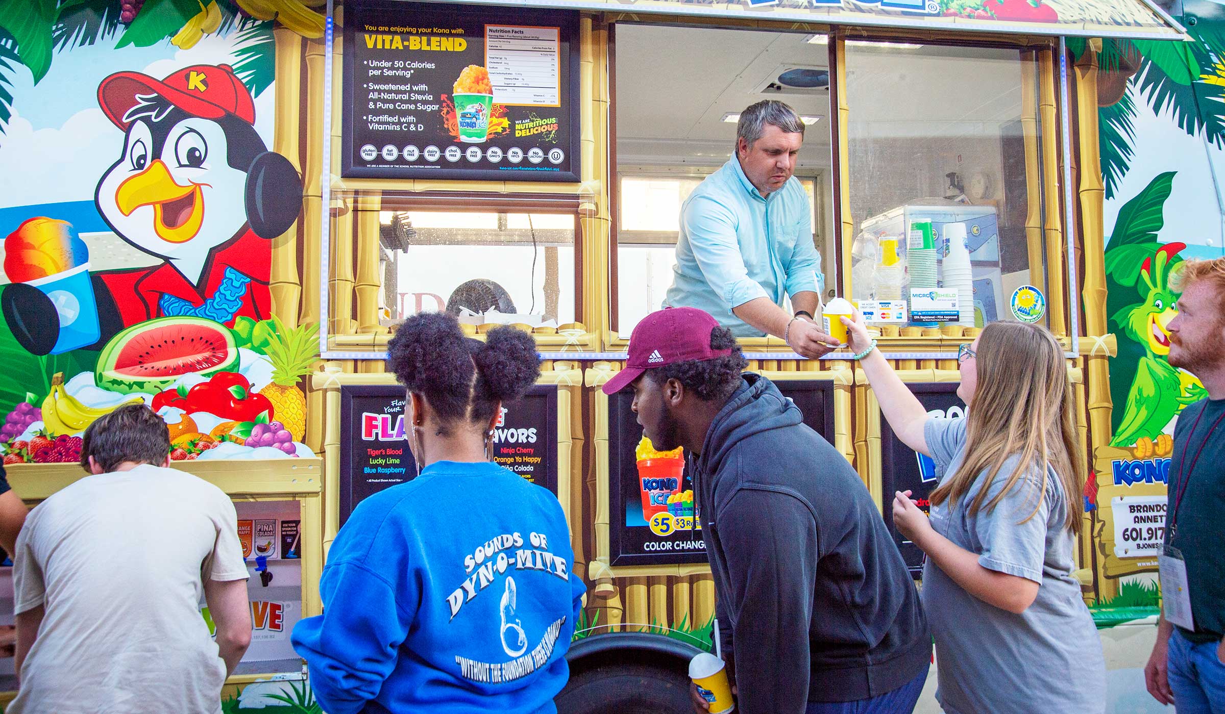 Students with snow cone cups in front of colorful truck