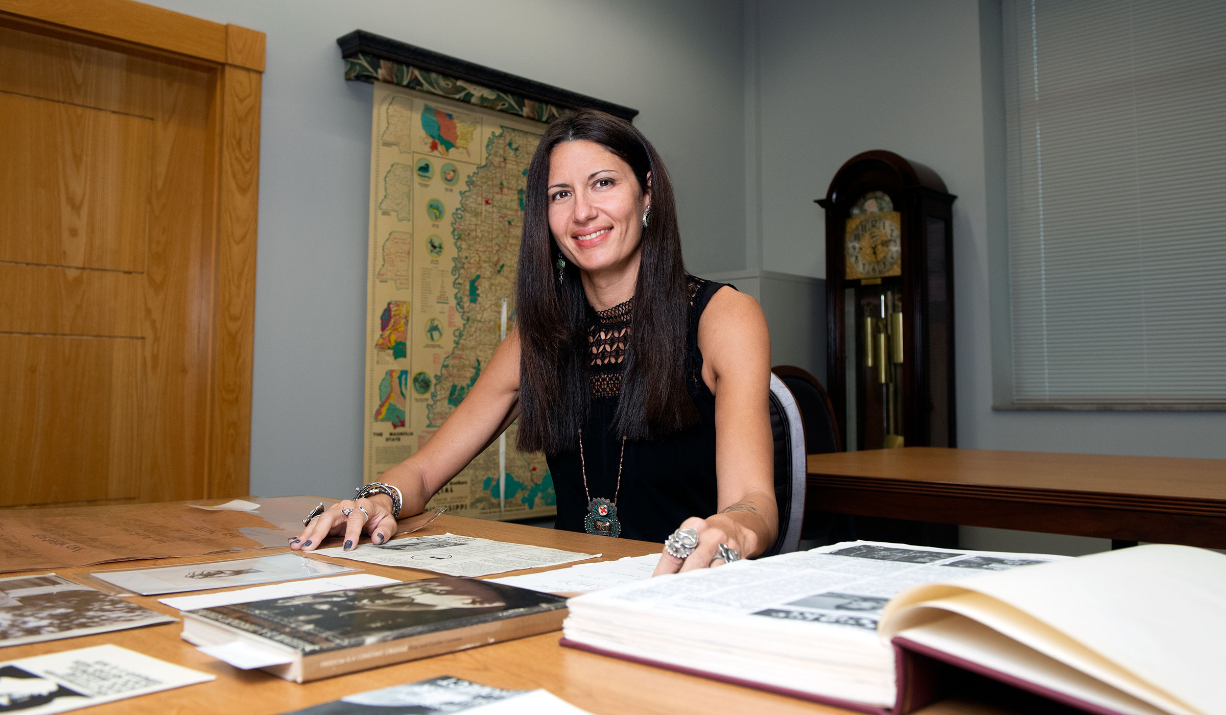 Woman behind table with books and art work and a map of Mississippi in the background