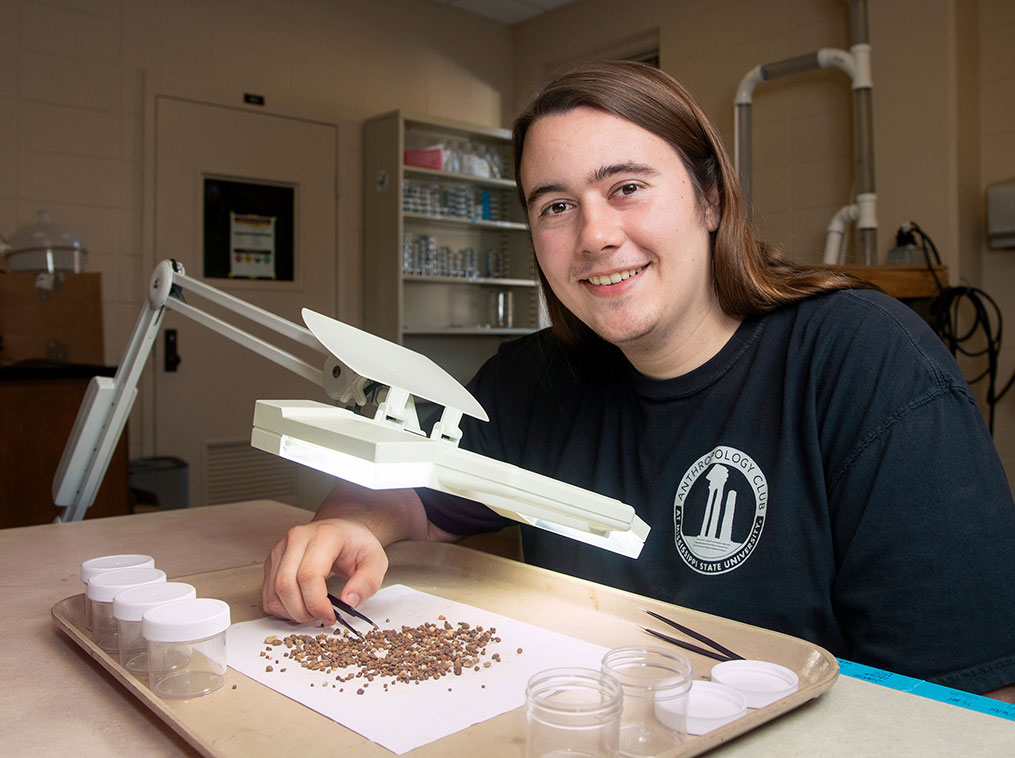 Dylan Colucci sorting fragments in archaeology lab at Cobb Institute.