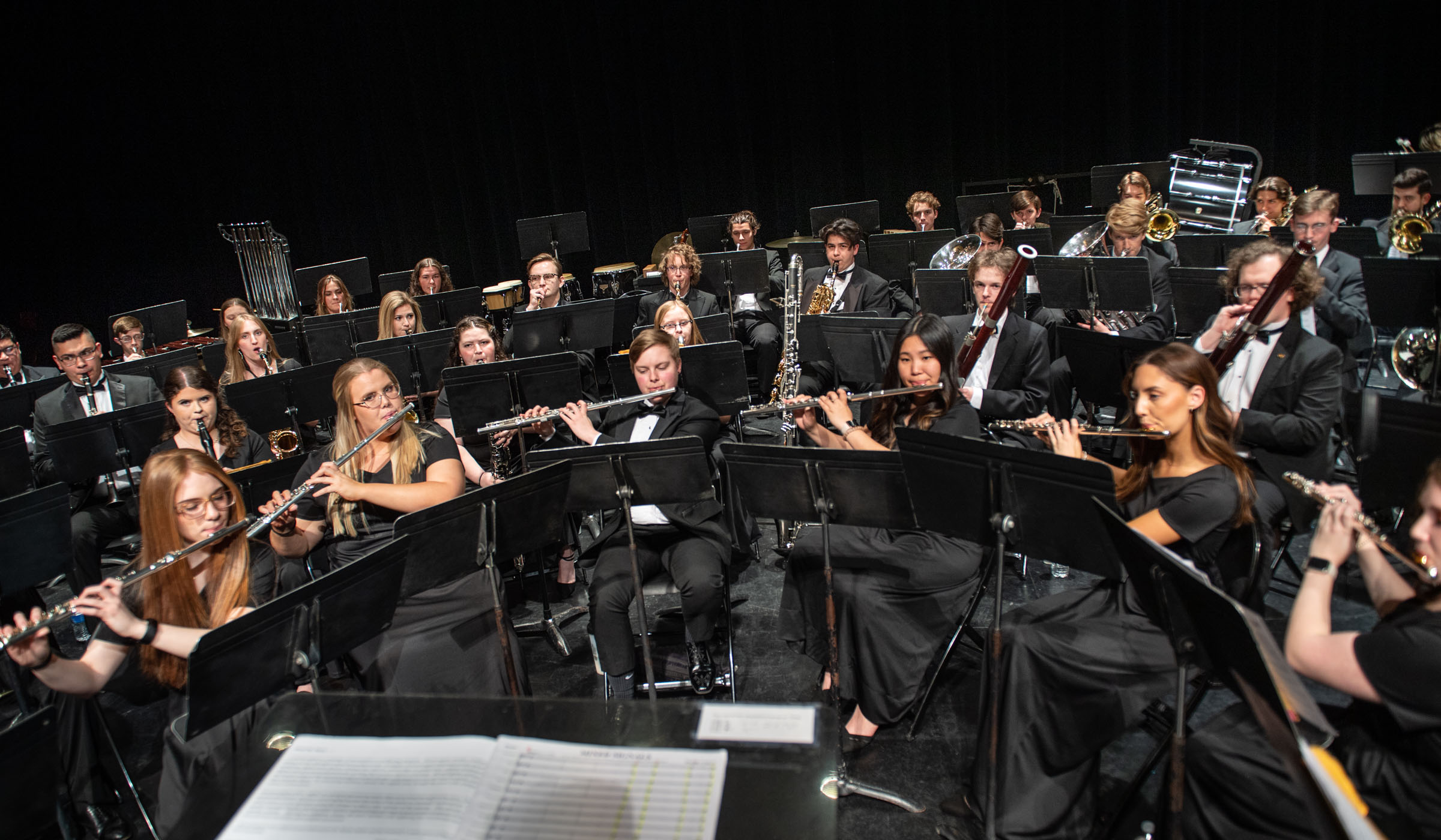 Wide angle of the Wind Ensemble student musicians playing on the stage of Bettersworth Auditorium, taken from the vantage point of the conductor&#039;s stand.