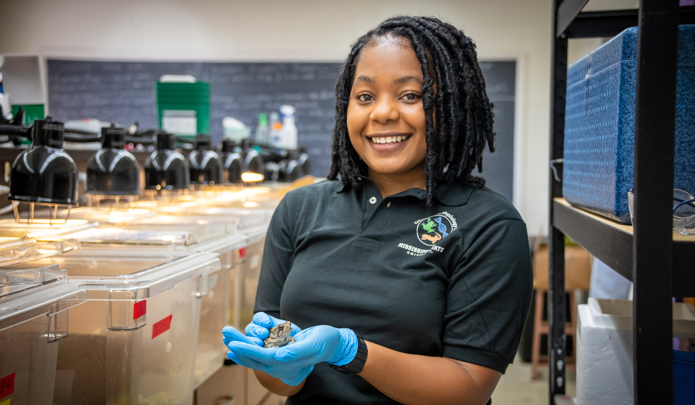 Namia Stevenson, pictured holding a frog in a lab setting.
