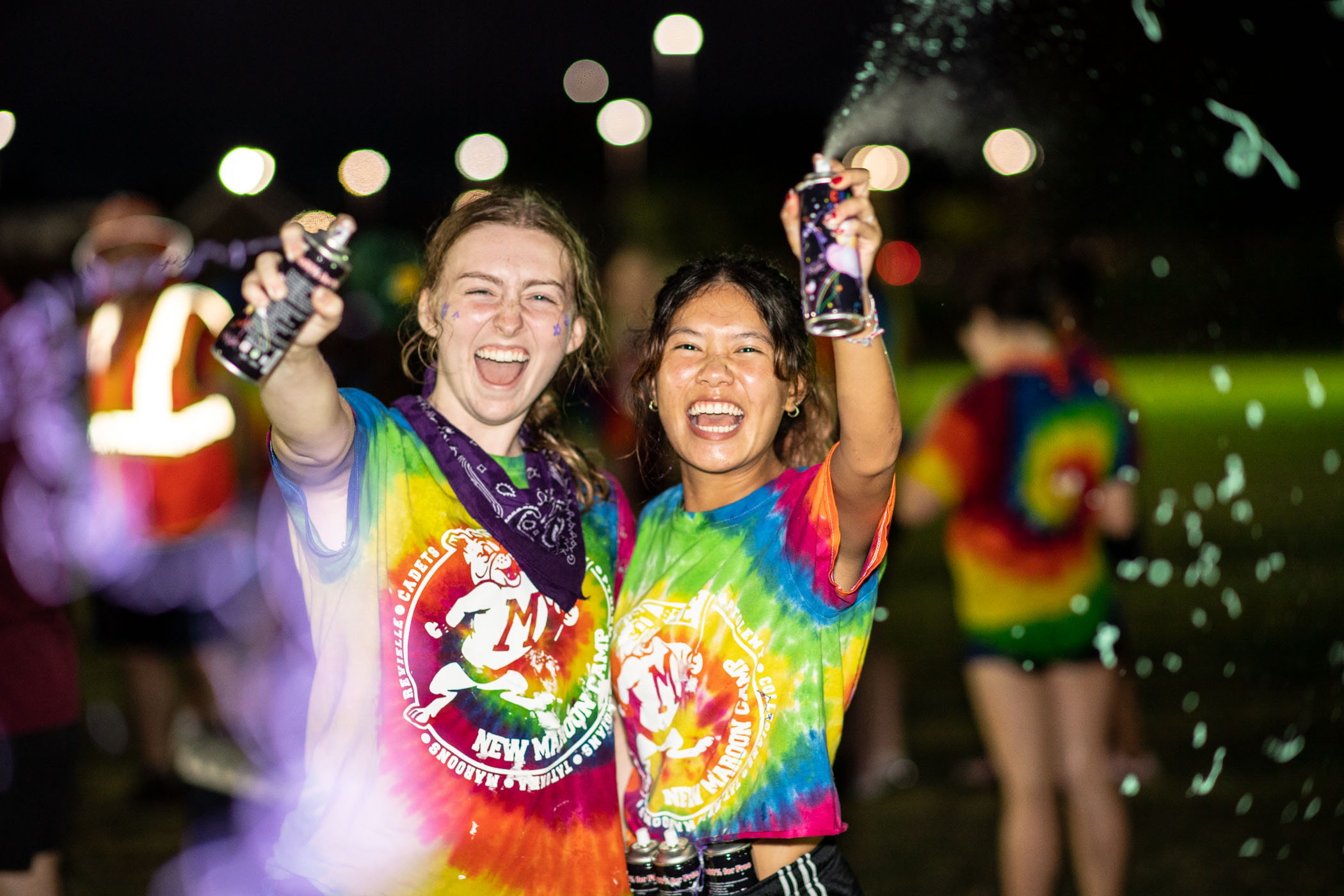 Two New Maroon Camp counselors grinning ear to ear spray the camera with silly string 