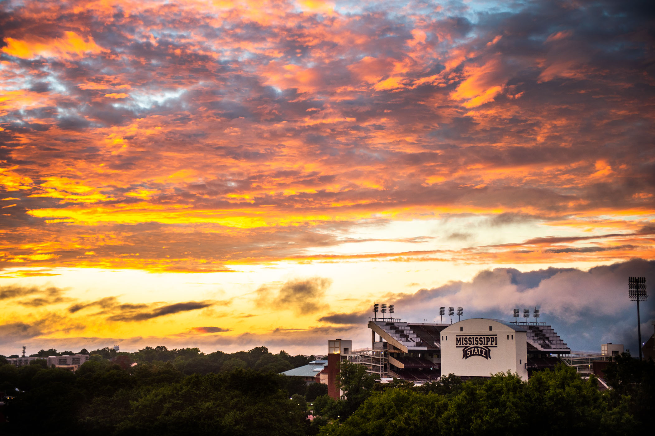A rich and colorful sunset packed with orange, gold, and pink gazes over Davis Wade Stadium