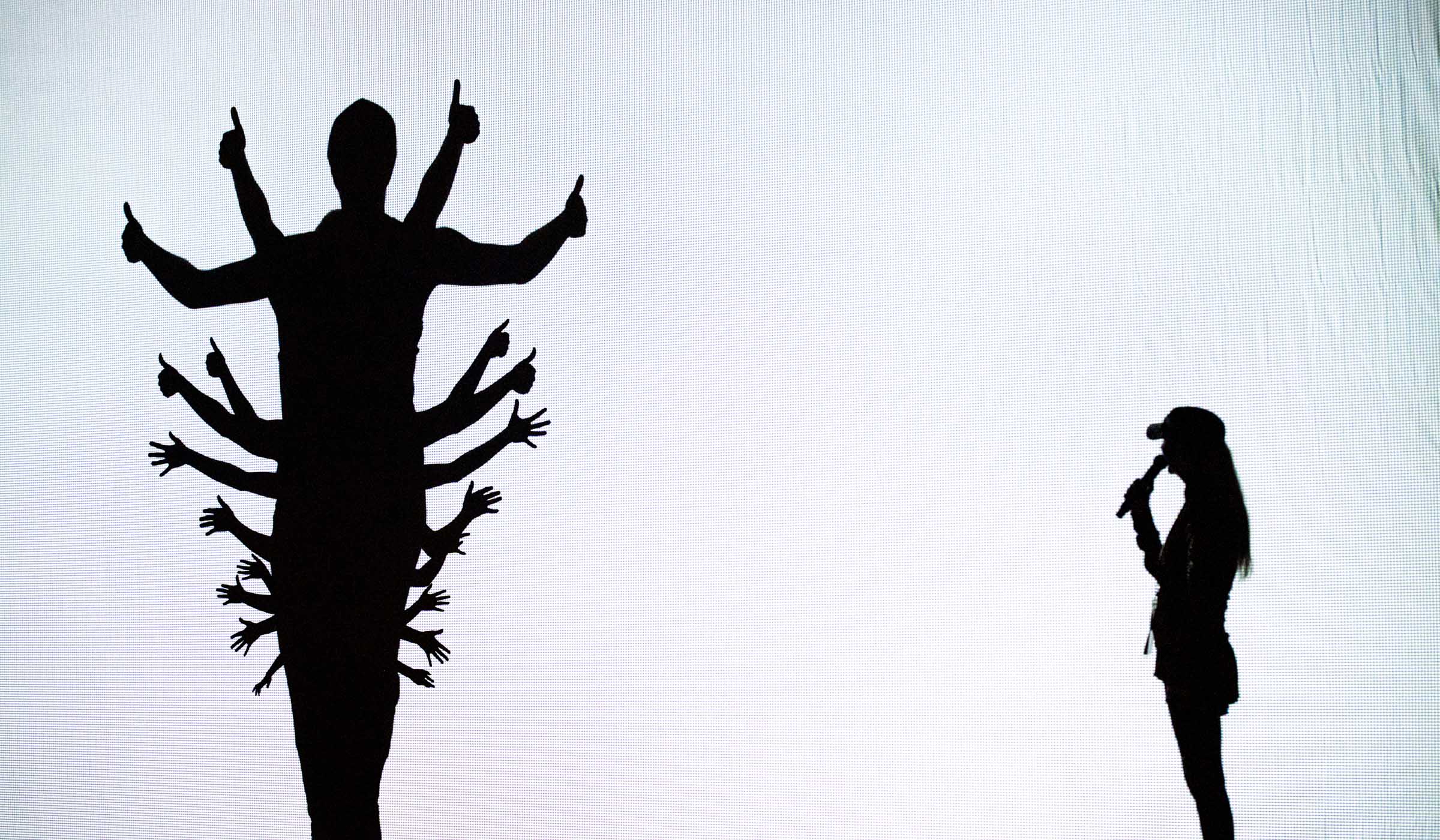 Dancers in the group The Silhouettes form a shadow tree on the left while their leader, Lynne Waggoner-Patton, narrates with a microphone to their right.