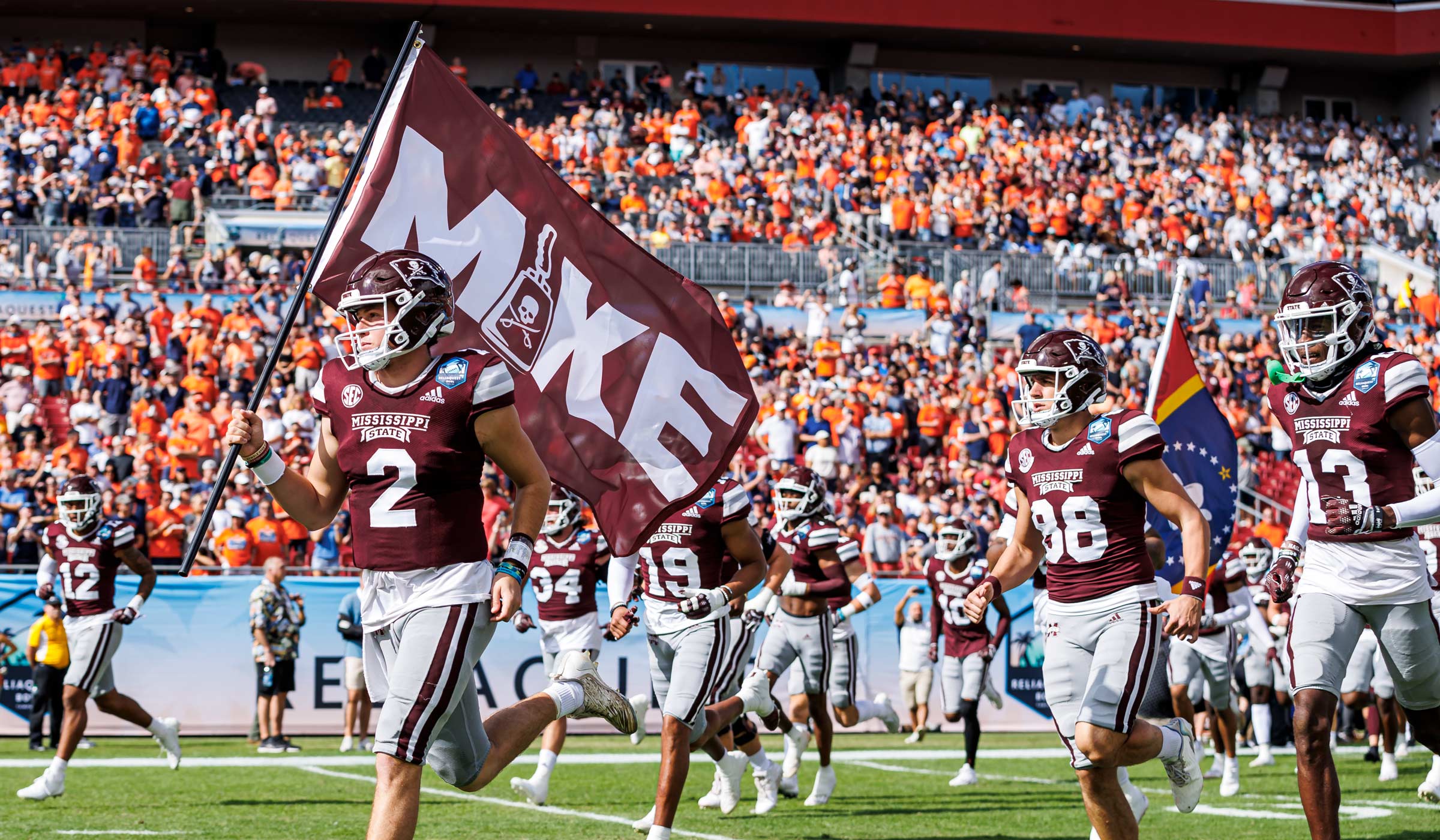 MSU Quarterback Will Rogers runs with the MIKE flag in honor of Mississippi State Late Head Coach Mike Leach before the ReliaQuest Bowl versus Illinois.