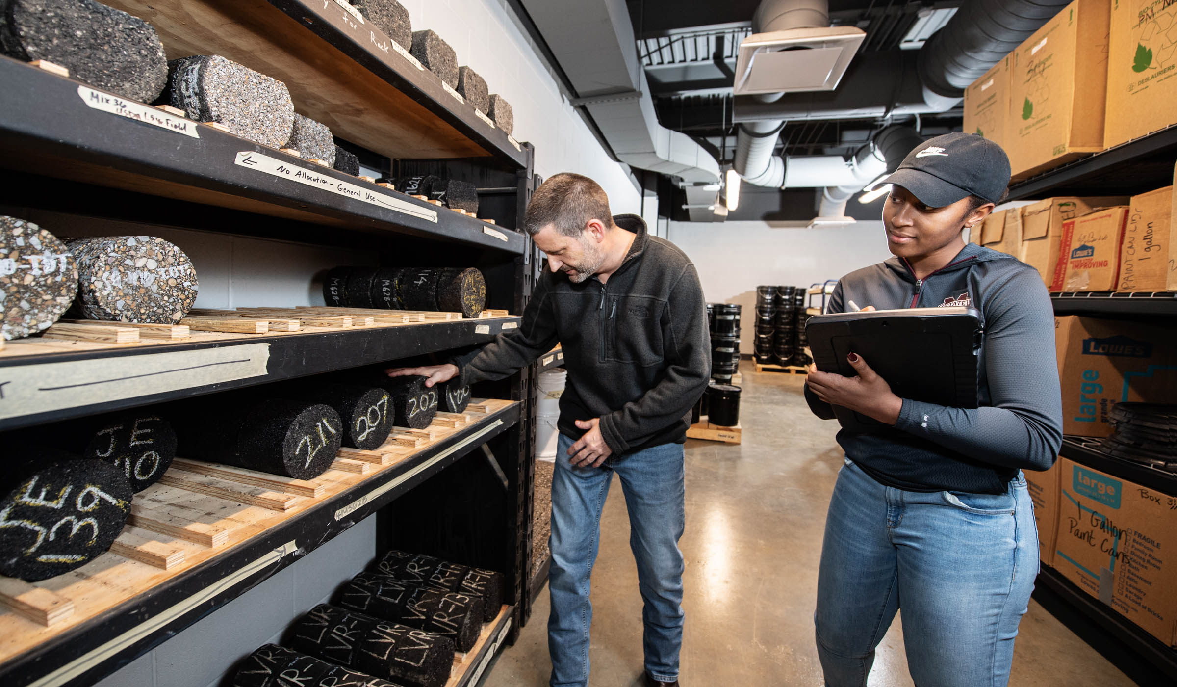 Civil Engineering Professor Isaac Howard and graduate student Jessica Lewis take note of asphalt research samples in Rula&#039;s materials storage room, which houses thousands of asphalt specimens of various ages.