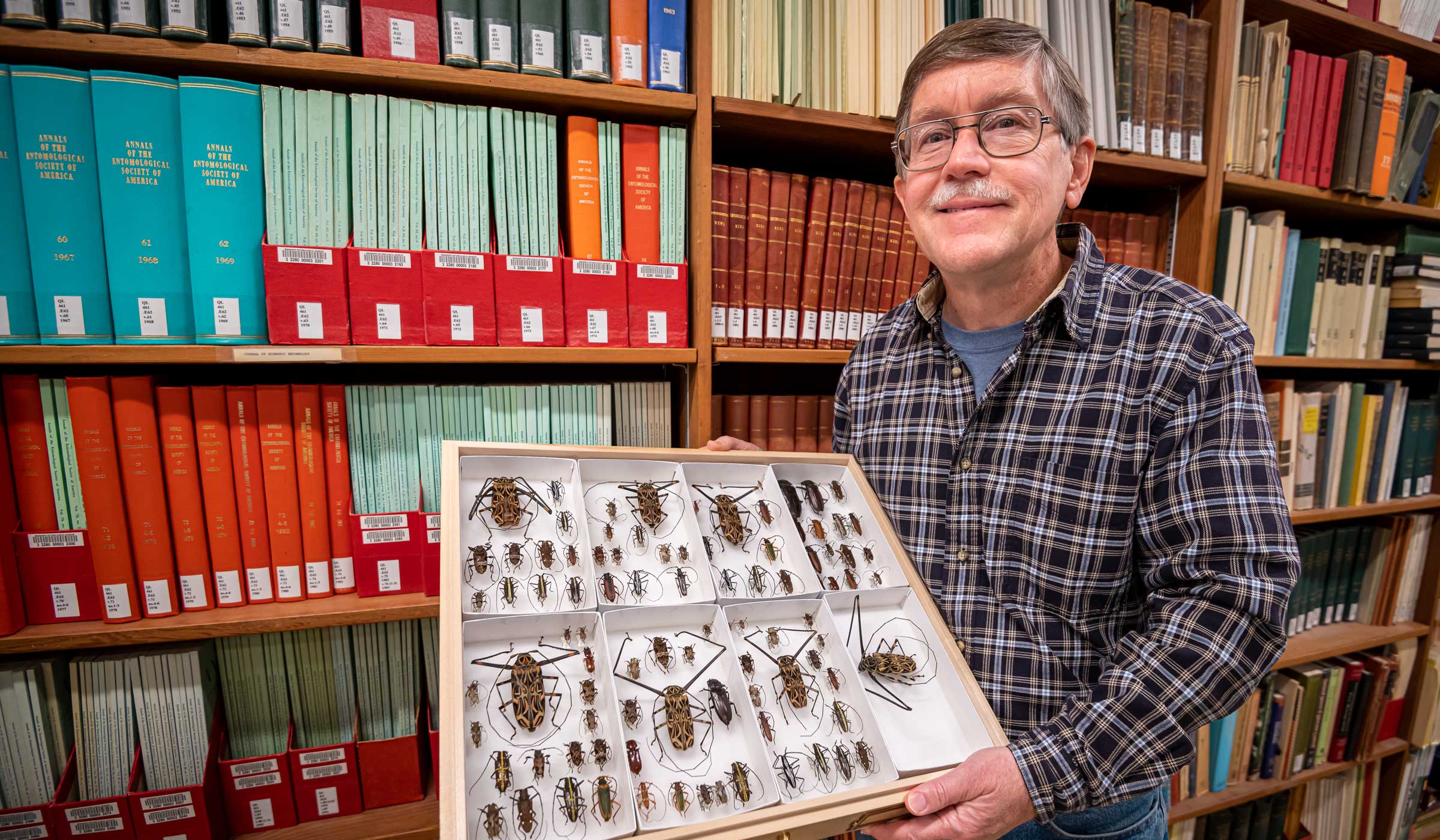 Picture of Terence Schiefer holding a display case full of beetles