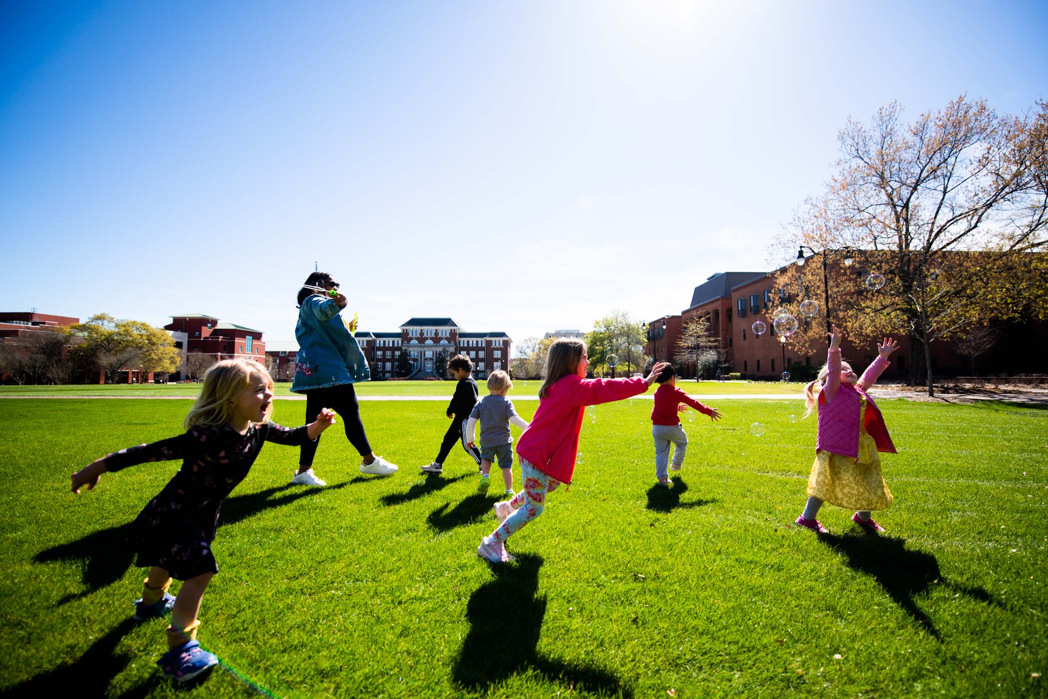 Preschoolers happily chase bubbles across the Drill Field.