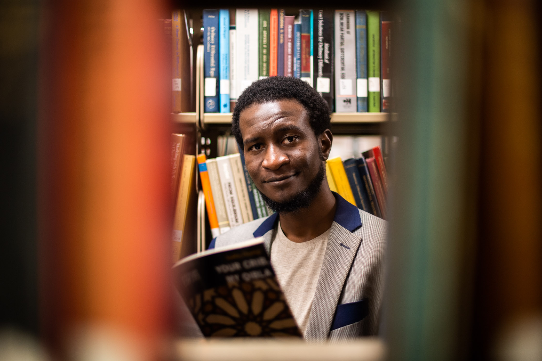 Saddiq Dzukogi, pictured among books in a library.