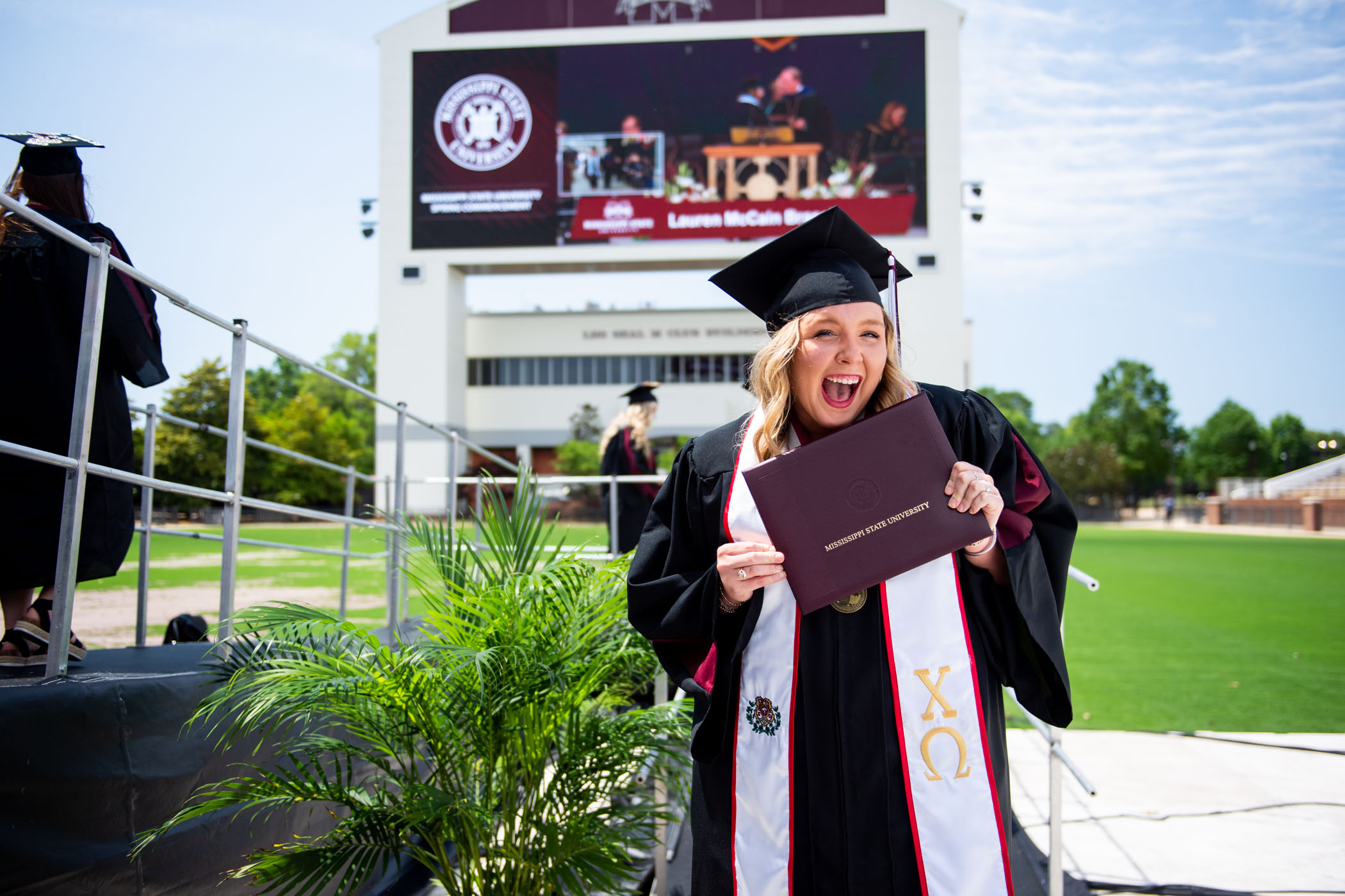 New MSU graduate Hope Kullman beams with a smile while exiting the Spring 2023 Commencement Ceremony stage with her diploma in hand