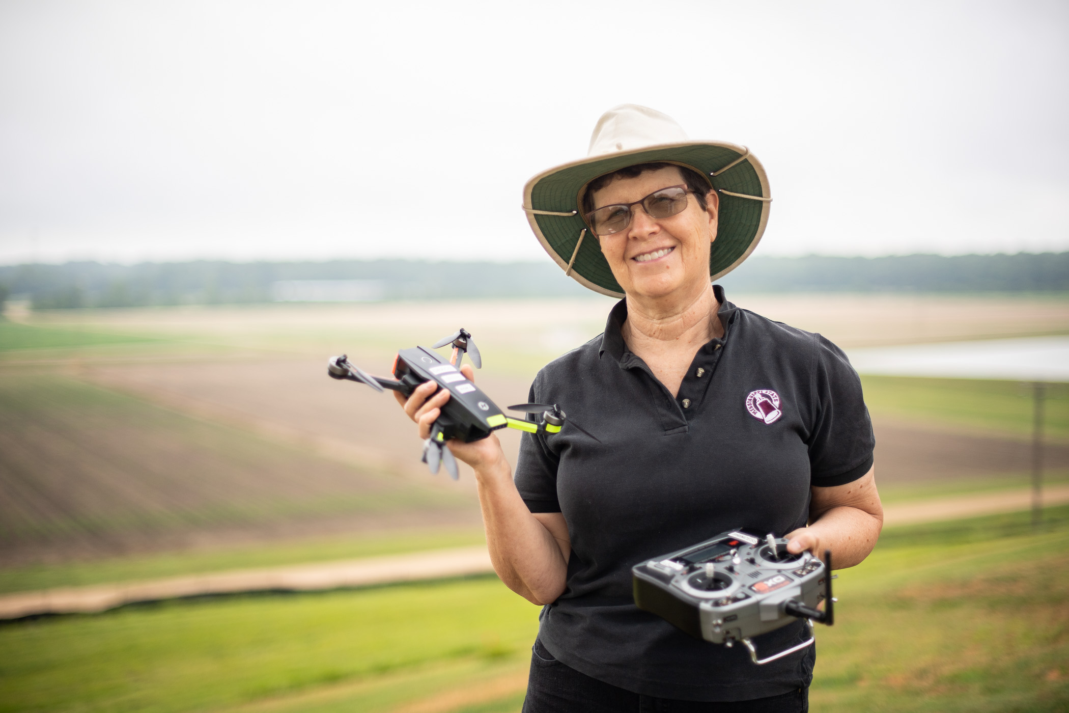 Amelia Fox, pictured holding a small drone in front of an agricultural field
