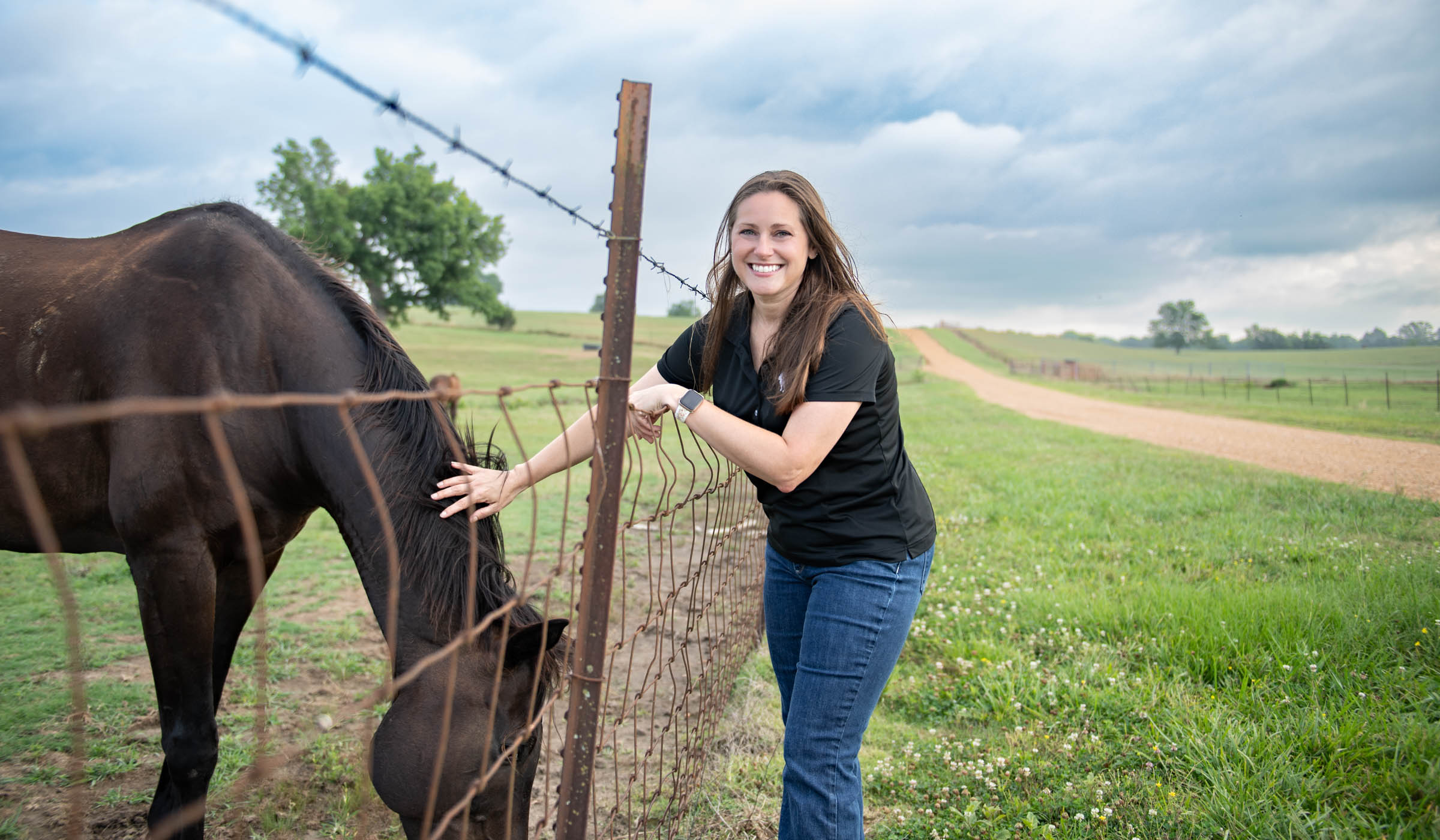 Melissa Inmon petting a horse through a fence