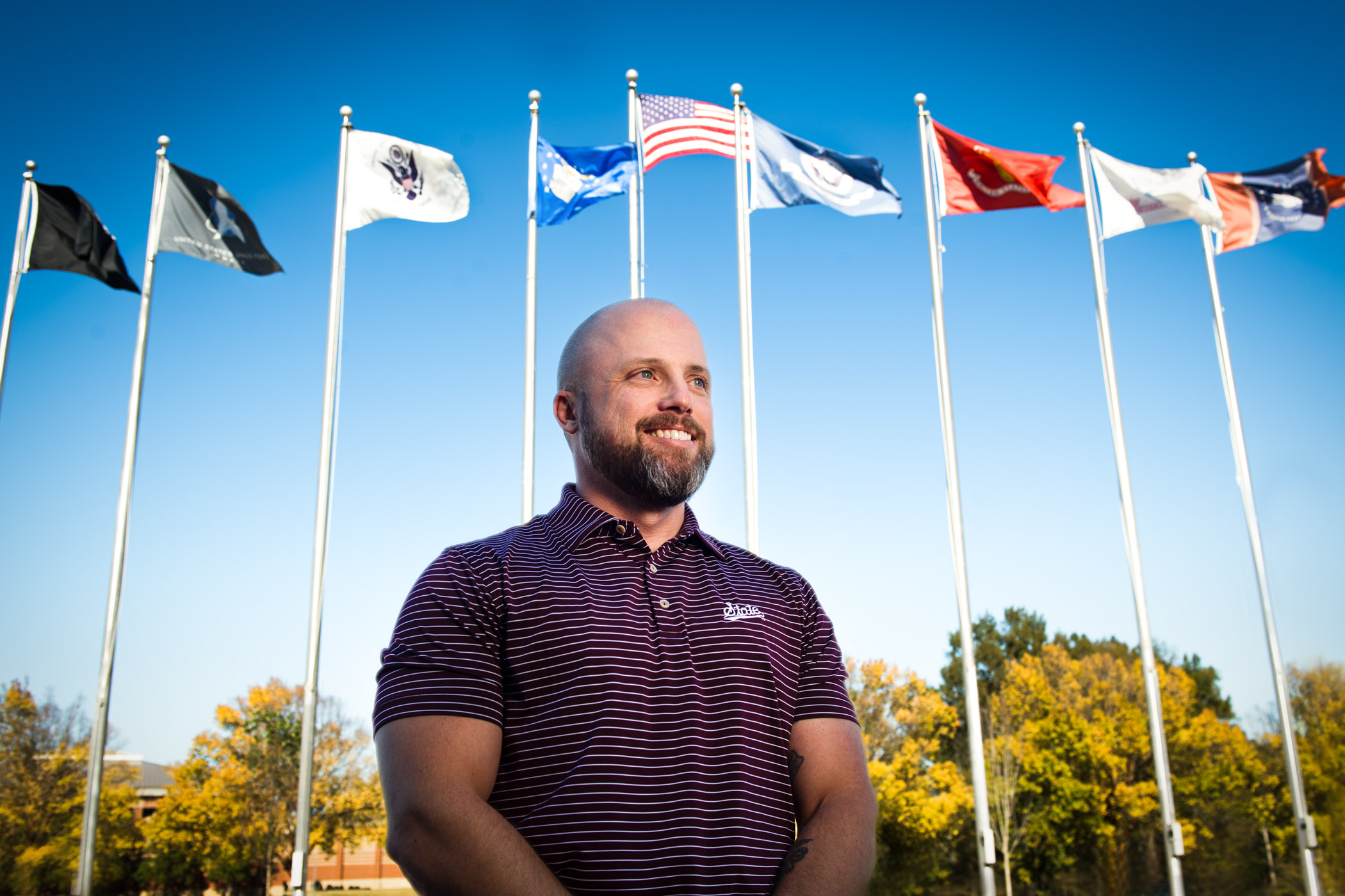 Justin Brown, pictured in front of flag&#039;s representing the U.S. military branches.