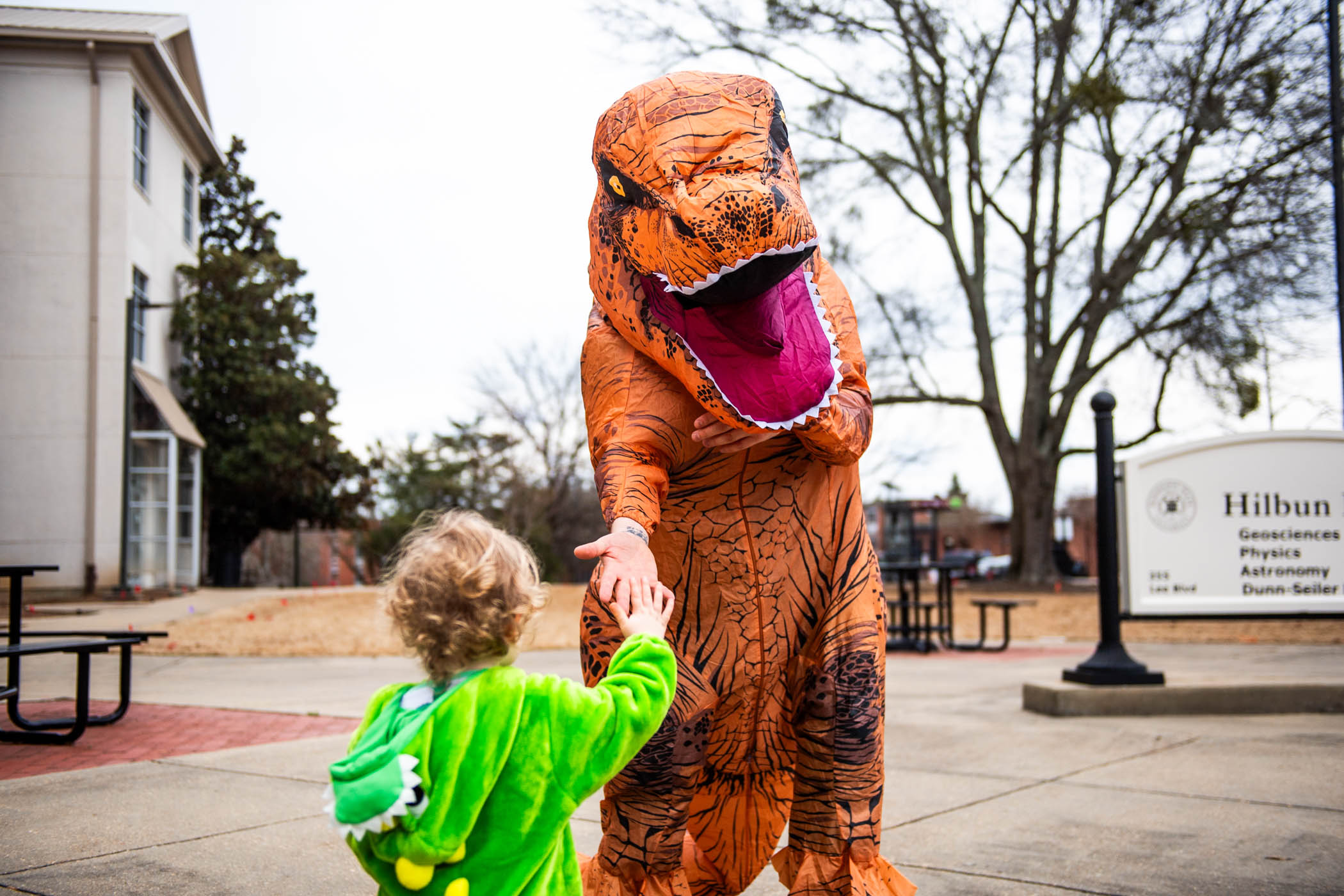 Jamie, a one-year-old explorer from Starkville, high-fives a &quot;T-Rex&quot; at MSU&#039;s annual &quot;Science Night at the Museums.&quot; Held at Hilbun Hall and Cobb Institute of Archaeology, this engaging event welcomed participants to fascinating exhibits and hands-on activities centered around the wonders of science.
