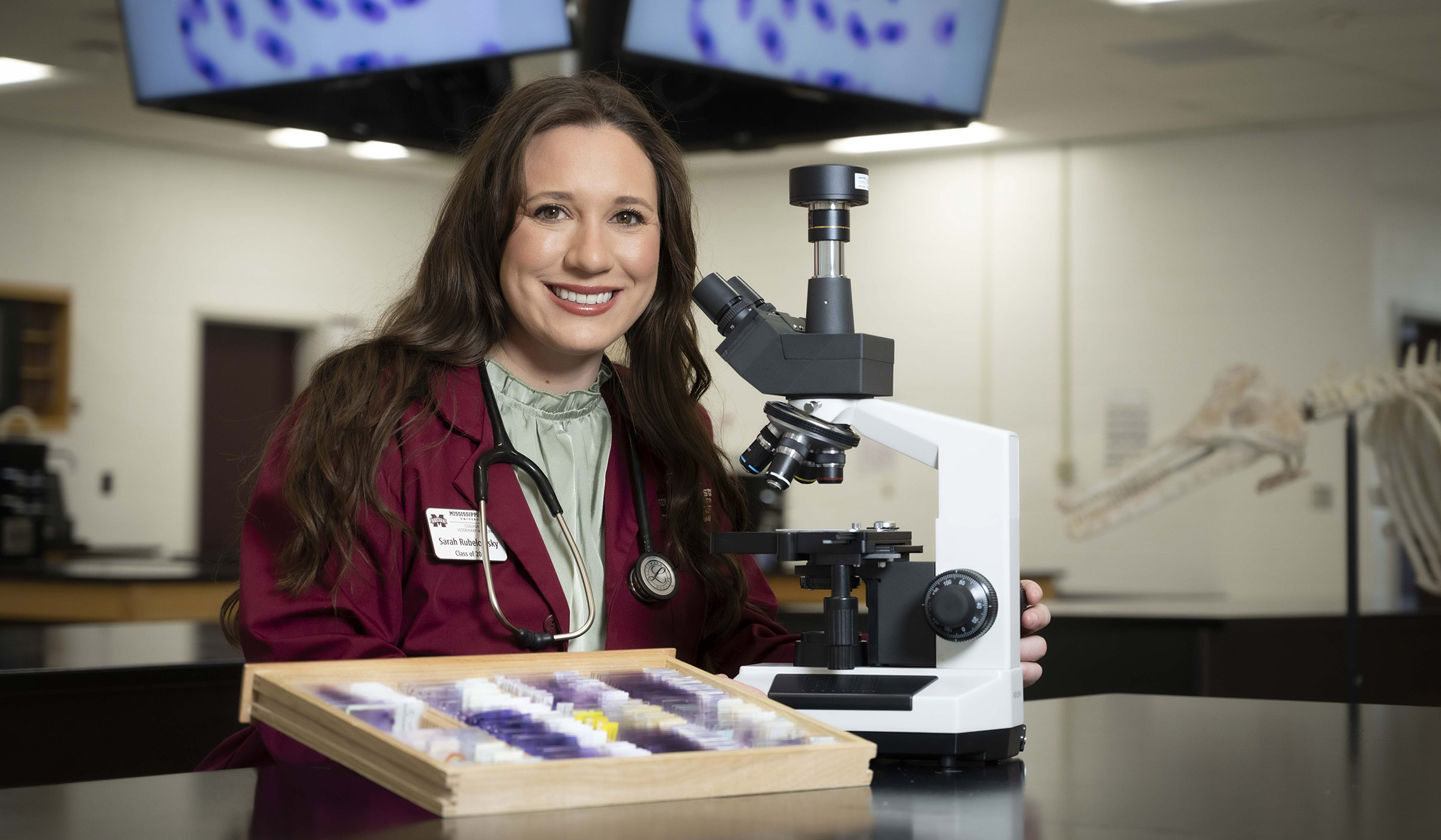 Sarah Rubelowsky, pictured in a lab next to a microscope