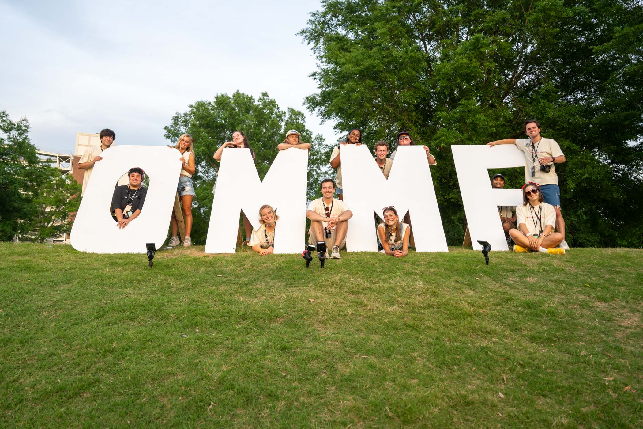 Members of Music Maker Productions gathered around the Old Main Music Festival sign. 