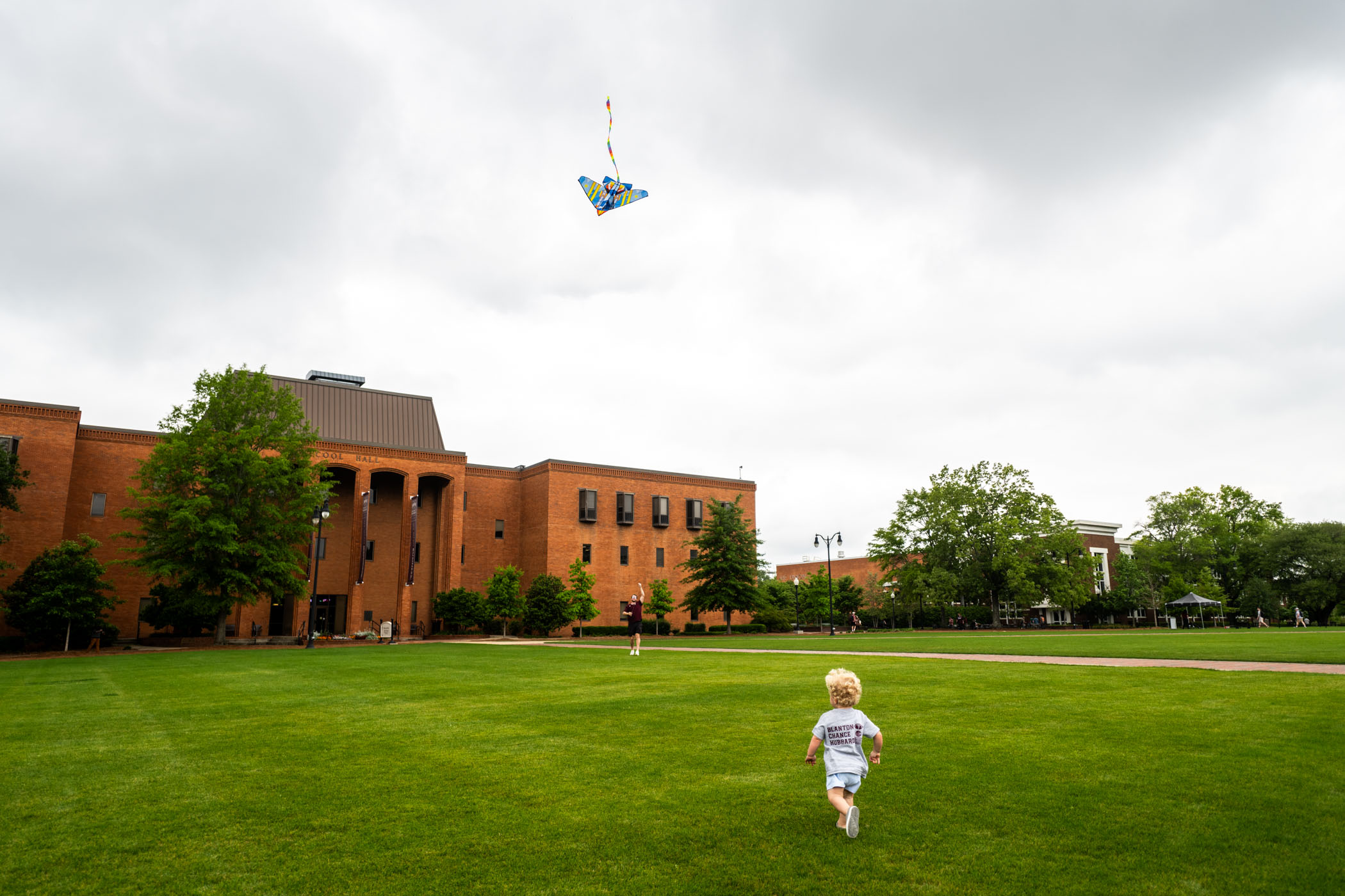 Two-year old Stafford Christensen of Madison chases a colorful, plane-shaped kite flown by his father, Brett, across the Drill Field Friday [April 19]. After a day of traveling, the family enjoys a calm moment on campus before the fanfare of Super Bulldog Weekend. 