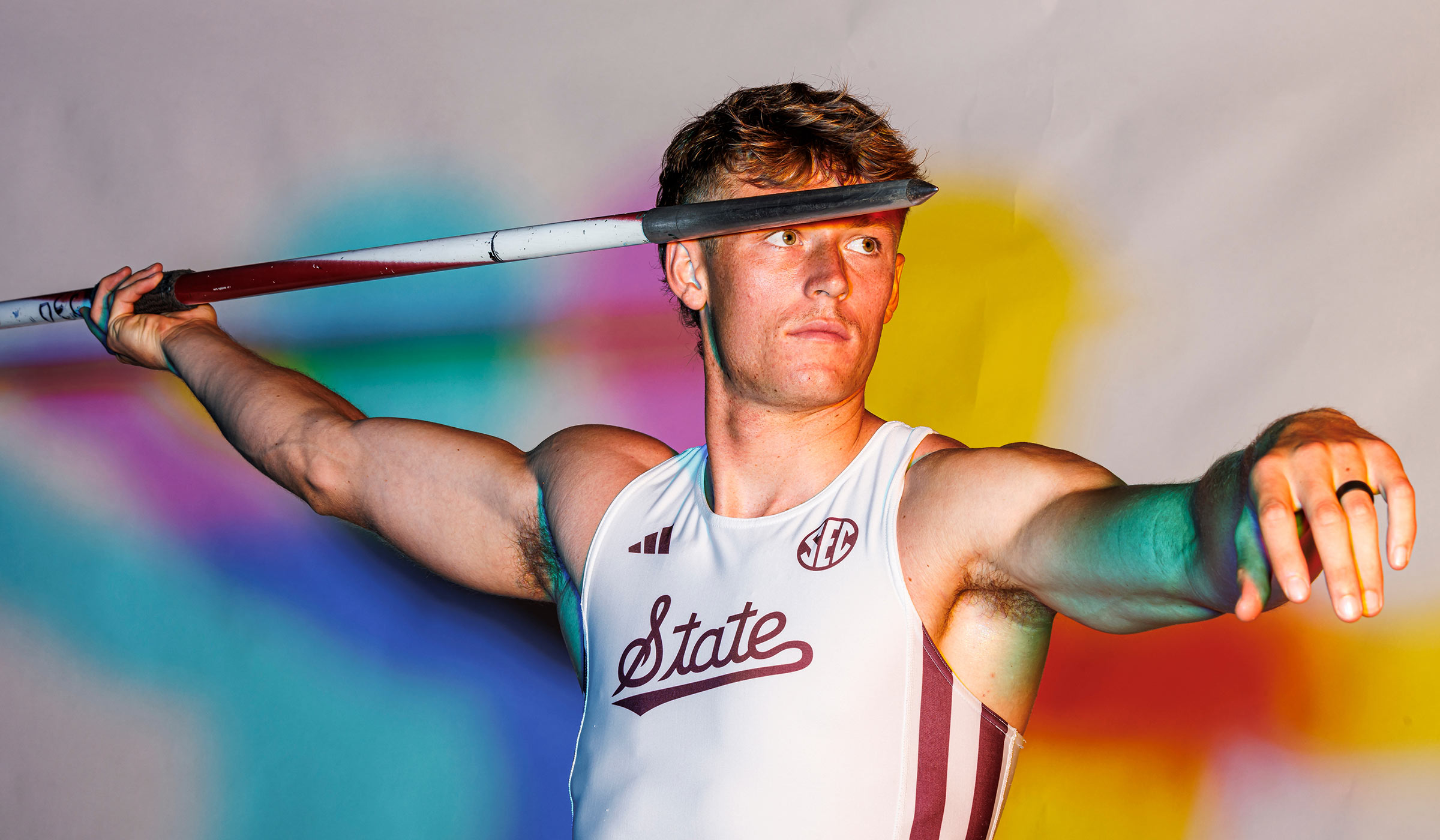 Man with javelin on multi-colored background