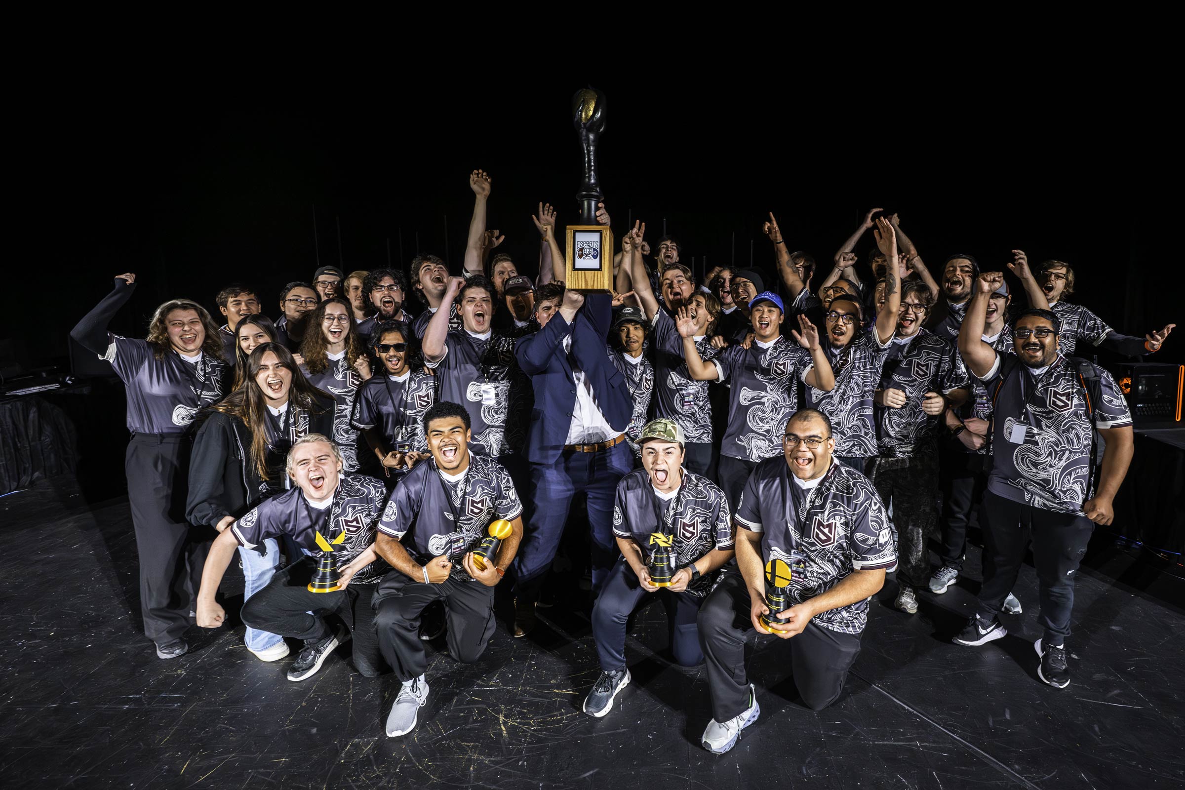 MSU Esports celebrates a 5-4 game victory over Ole Miss at the 8th annual Egg Bowl, proudly hoisting the golden egg trophy. The tournament, hosted in McComas theater, features live &quot;best-of-seven&quot; gameplay of popular competitive titles such as Rocket League, Marvel Rivals, Street Fighter Six, College Football &#039;26, Valorant, League of Legends, and Super Smash Bros Ultimate. 