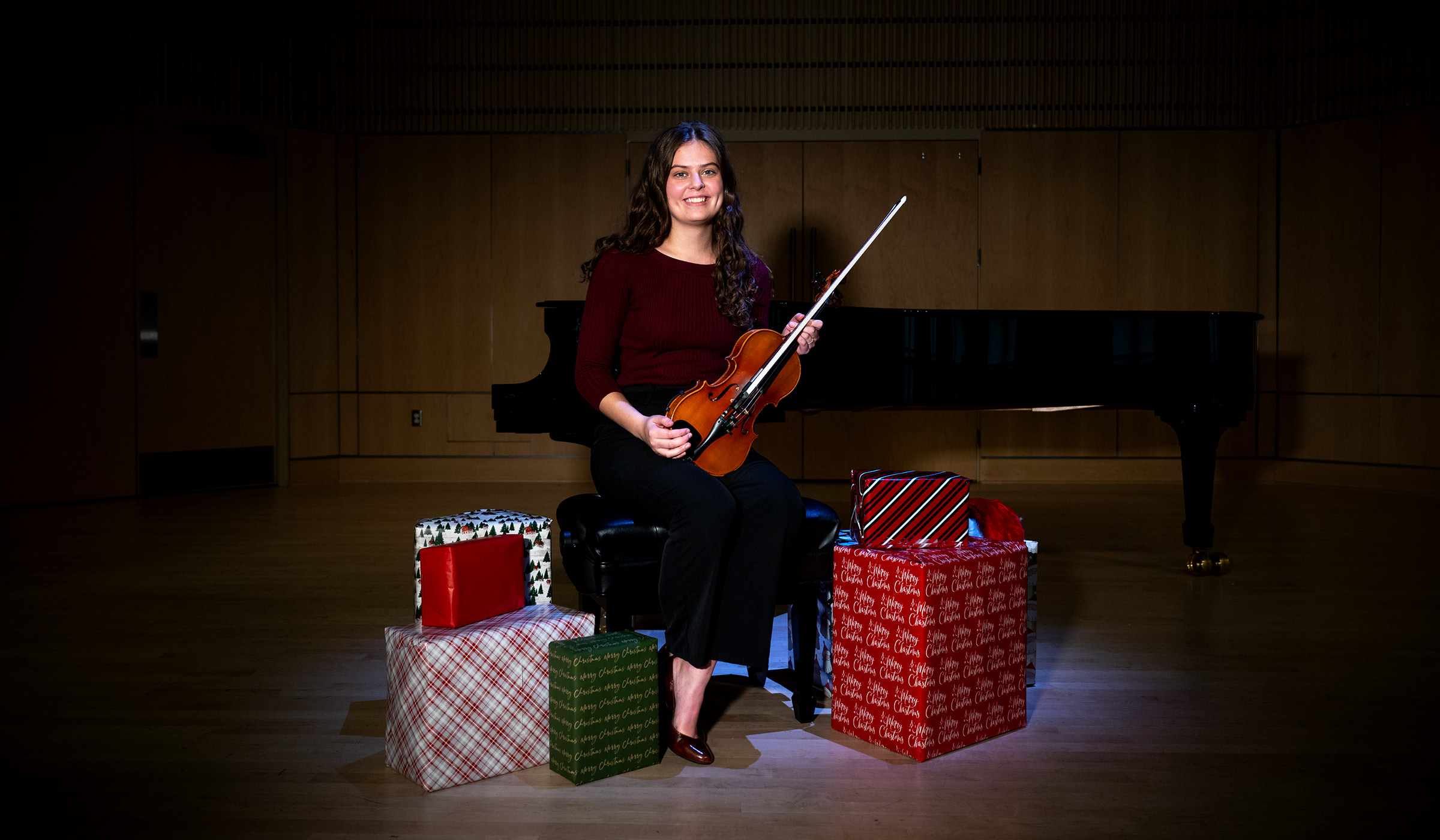 Woman playing violin in front of presents