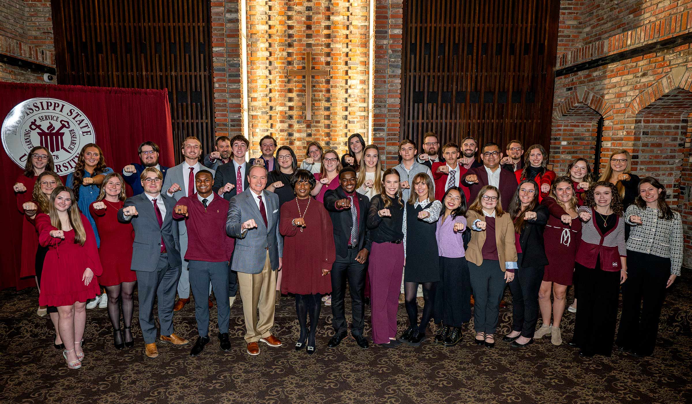 Group of students pose in the Chapel of Memories with class rings held out.