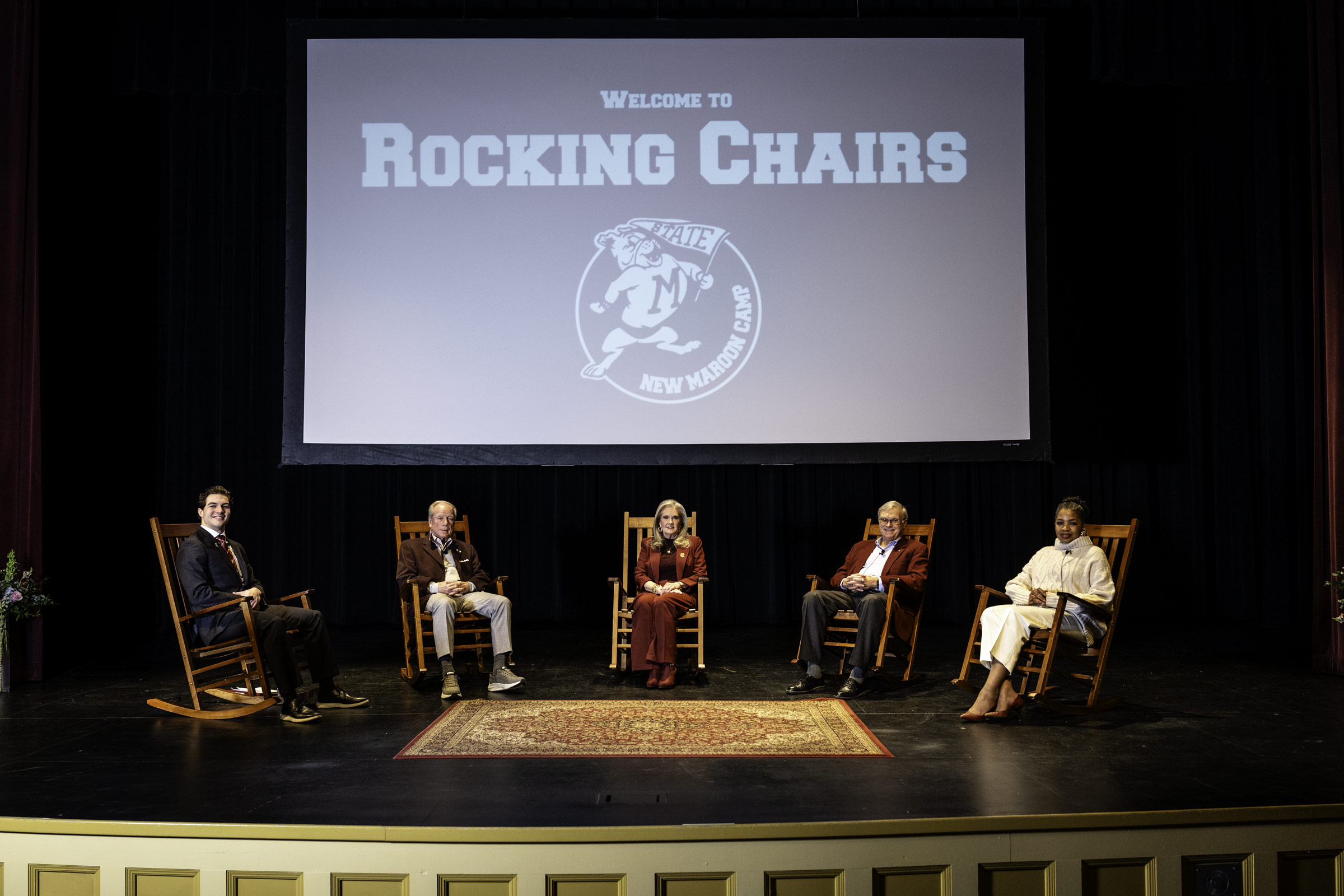 four people on stage sitting in rocking chairs