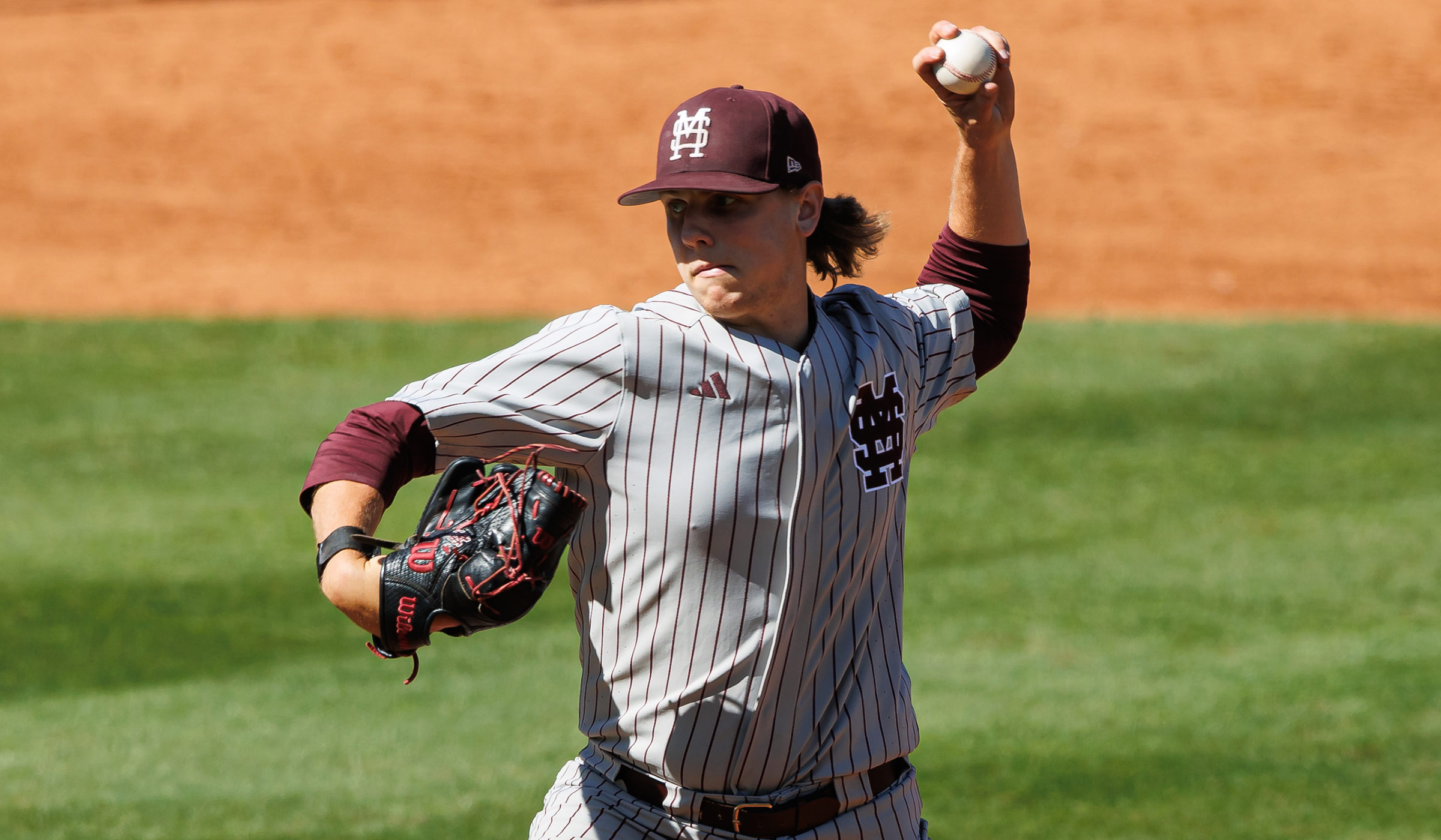 Guy in gray baseball uniform with maroon pinstripes pitching from his left hand.