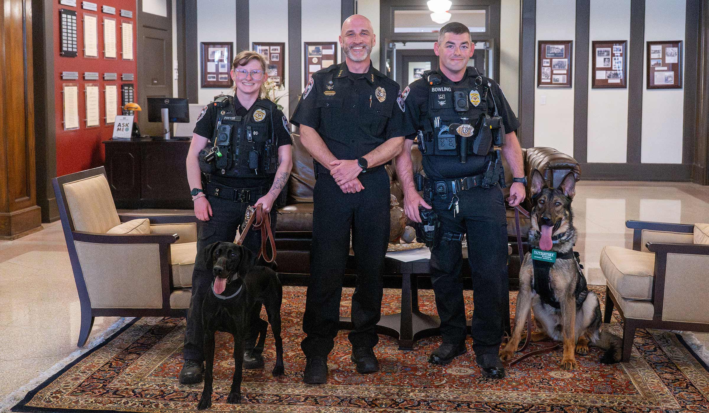 Three police officers in uniform with a black German Short-Haired Pointer and German Sheperd