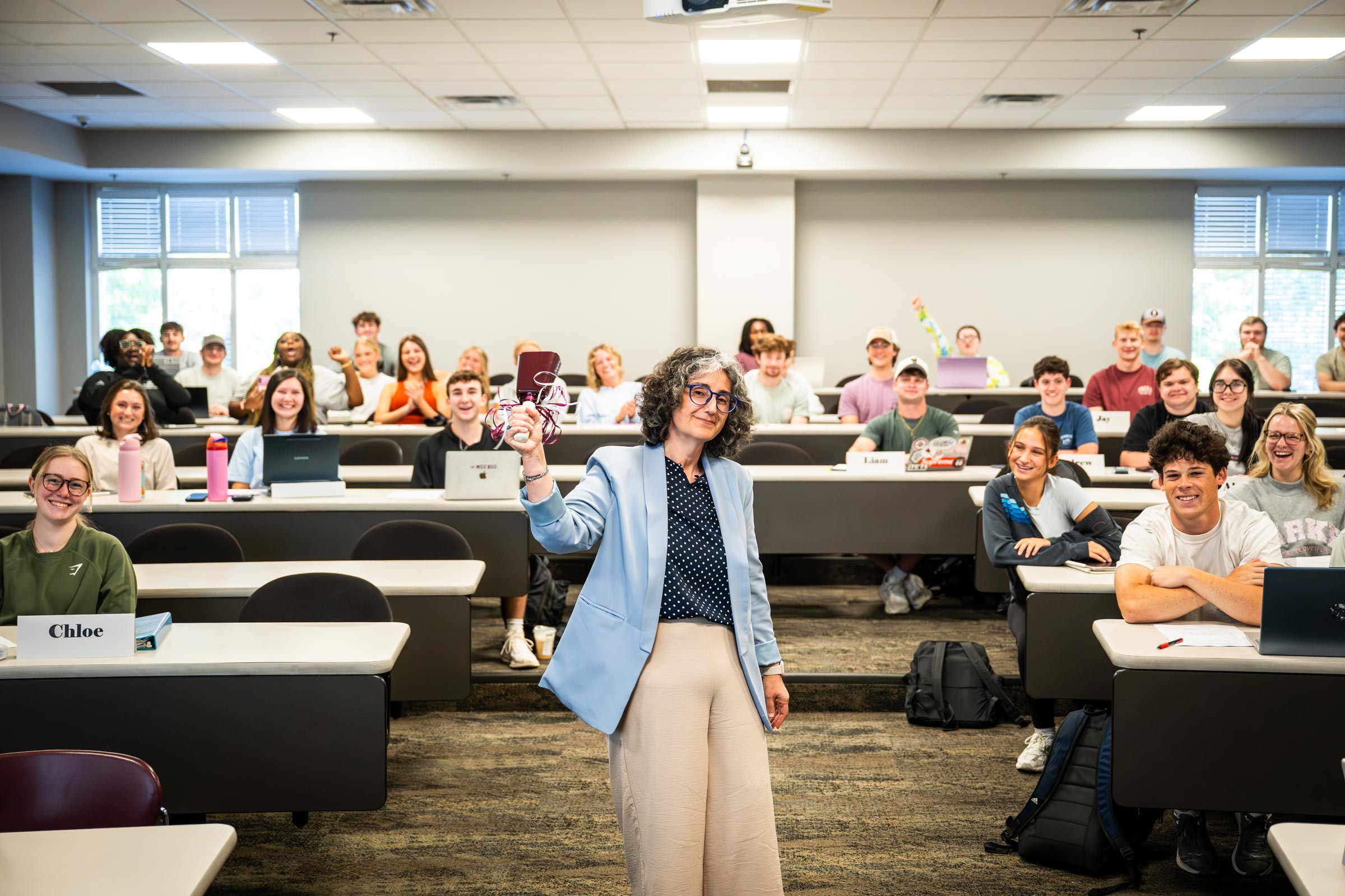 photo of instructor ringing a cowbell in front of excited studets