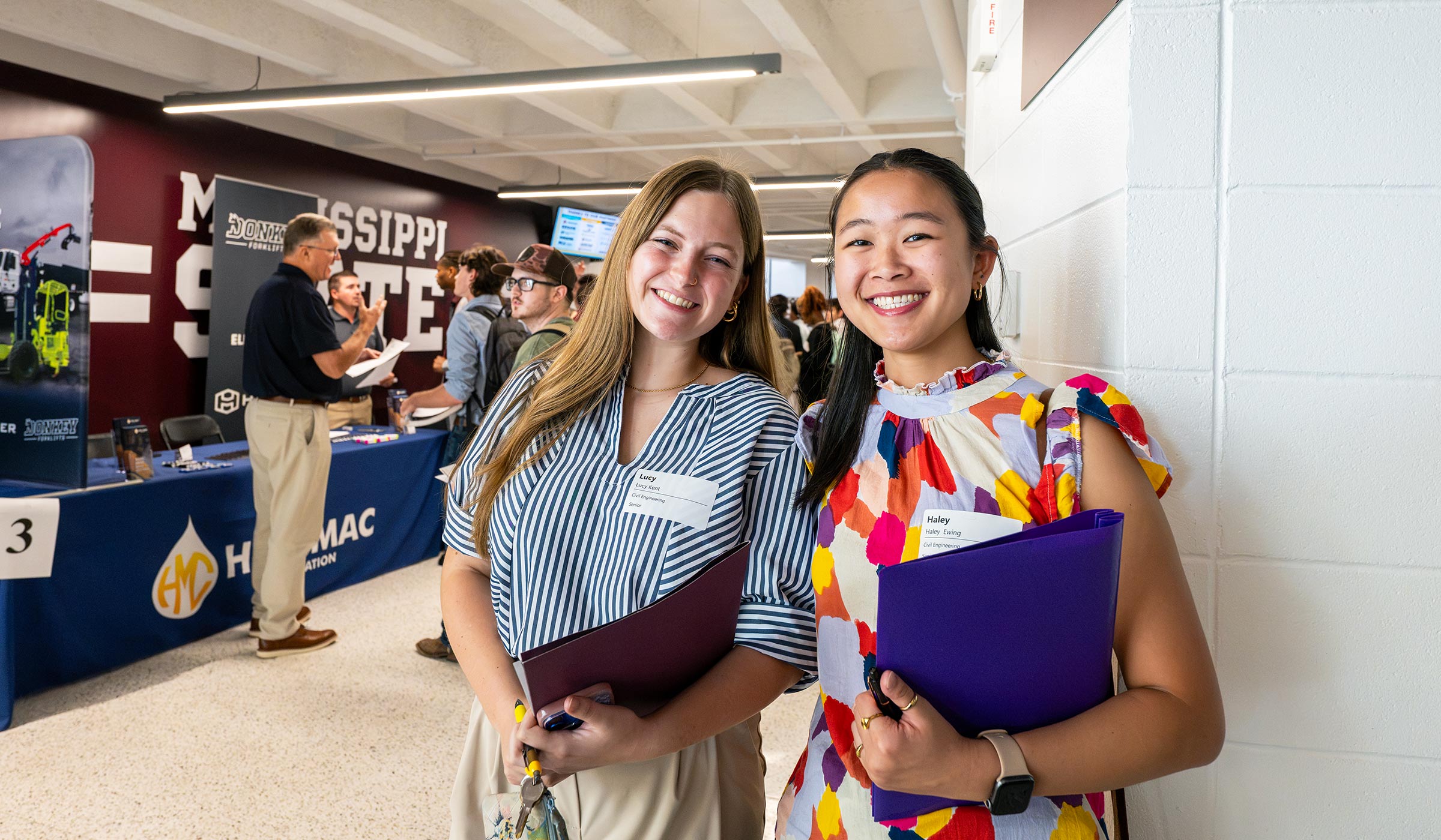 Two students pose with folders at the Career Expo in the Hump.