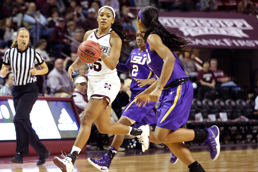 Female MSU basketball player dribbling ball around opponent in purple and gold