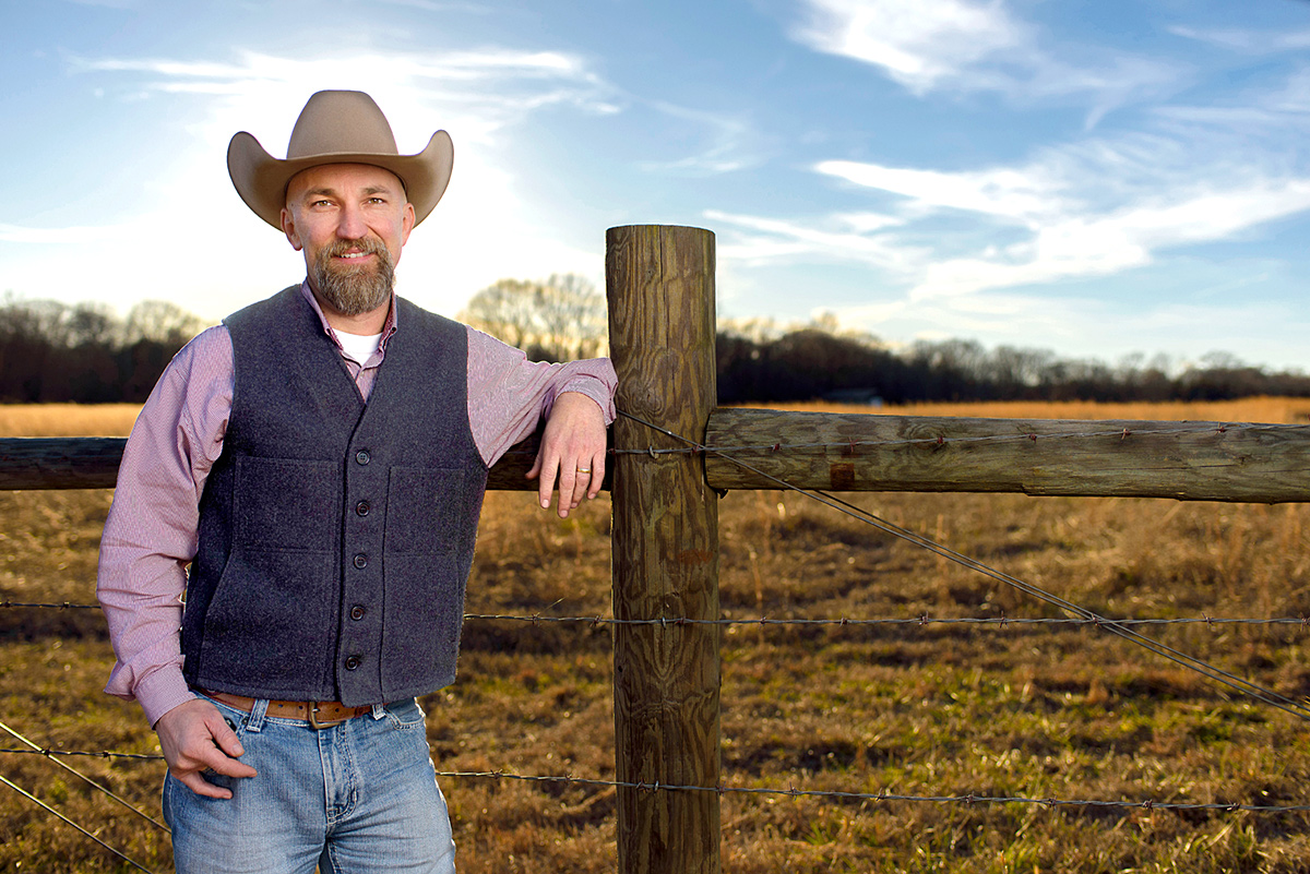Ty Jones, pictured leaning on a fence post in a pasture.