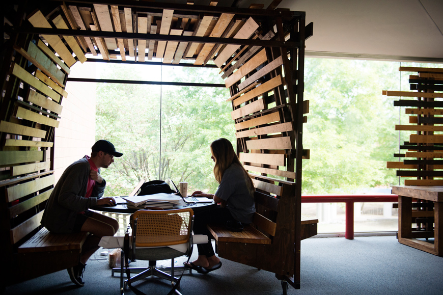 Architecture students Zachary Henry and Lara Lynn Waddell work on their final projects at backlit table.