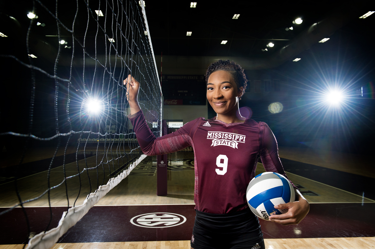 Khristian Carr poses in uniform next to the volleyball net at the MSU court.