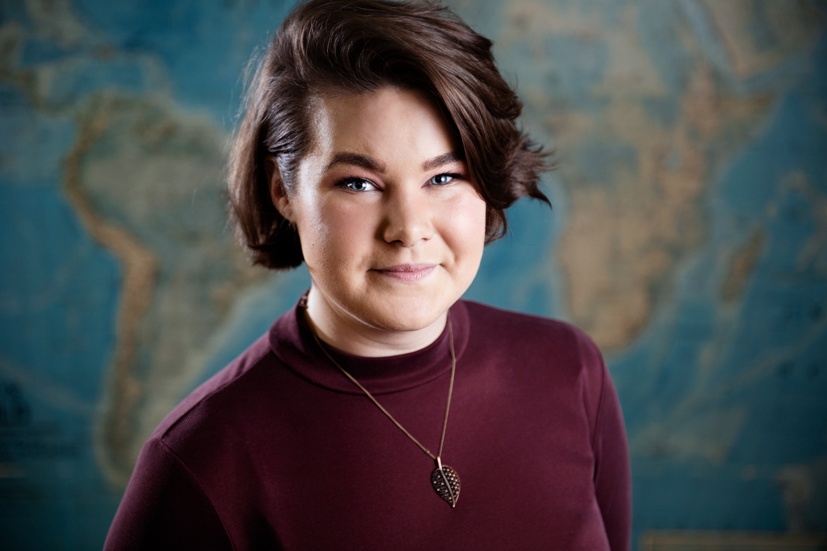 Madeline "Maddie" Casey, pictured in front of a global map.