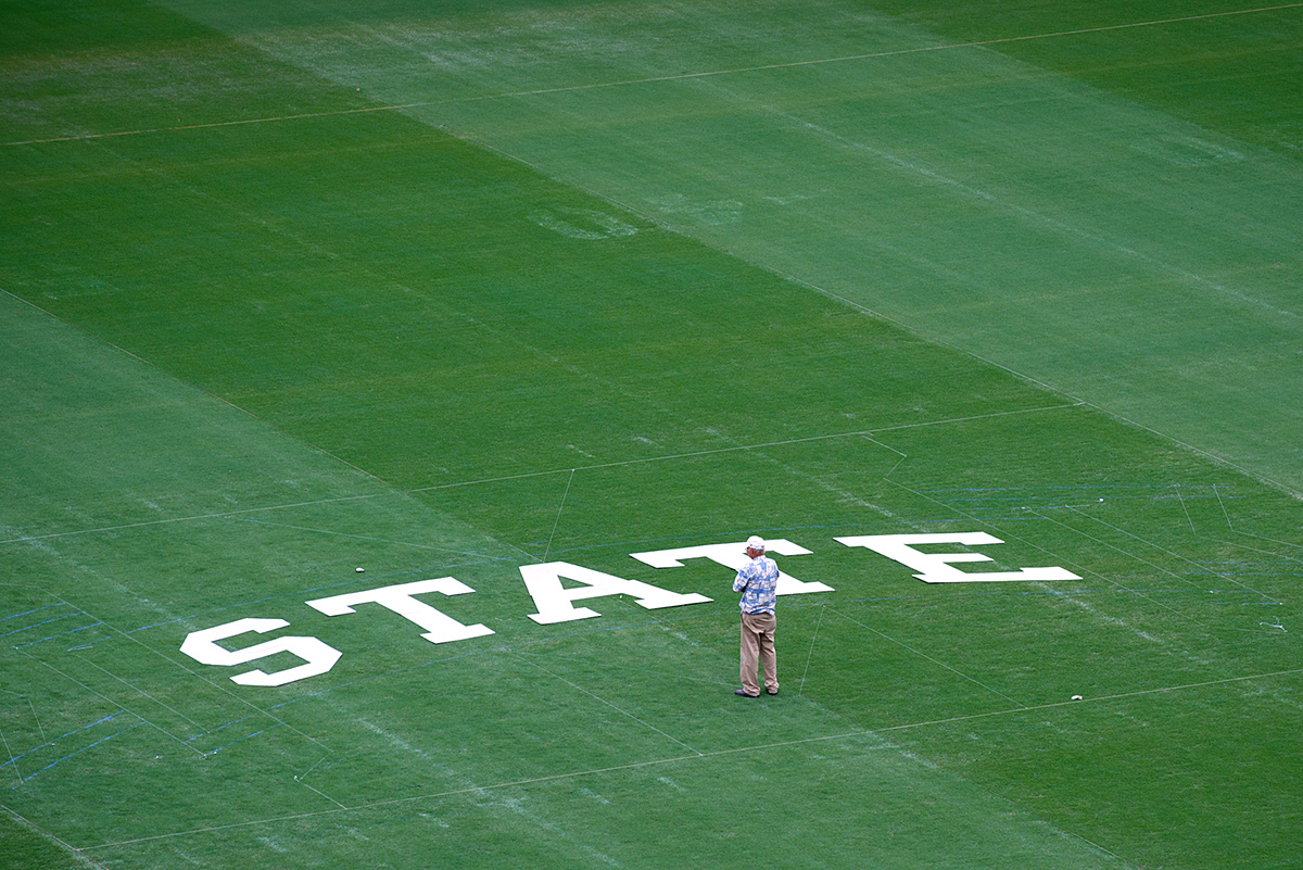 Buddy Gentry looks over letters on football field before painting.