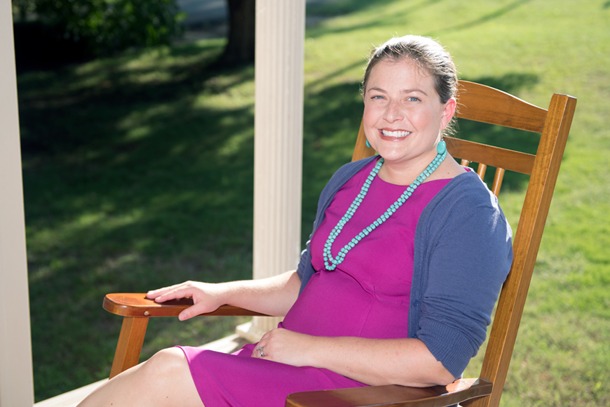Kim Kavalsky sitting in a chair on a sunny porch front.