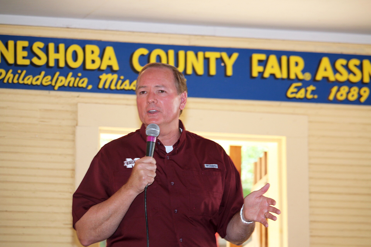 President Keenum in maroon shirt speaking with microphone at the Neshoba County Fair.