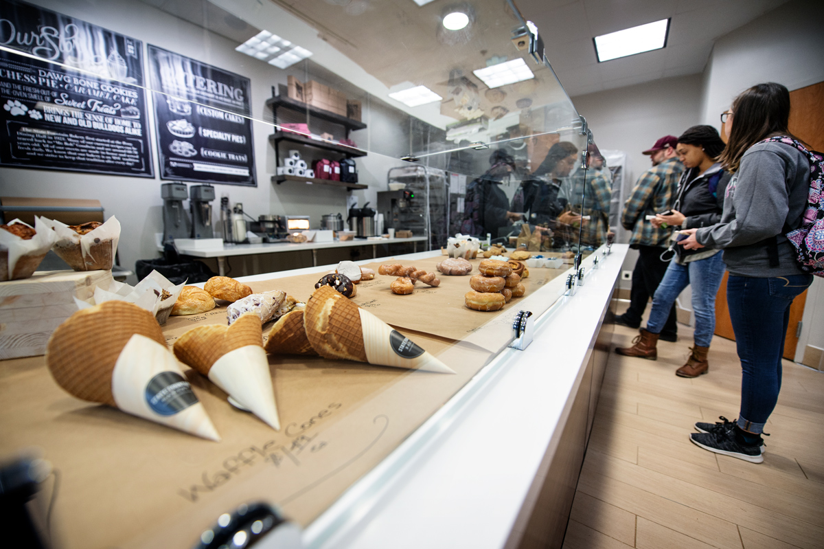 A line of customers awaits service at the State Fountain Bakery&amp;#039;s new location, with baked goods on display.