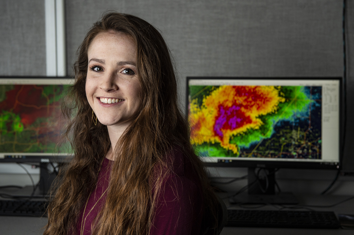 Caroline MacDonald, pictured in front of computers with severe weather warnings.