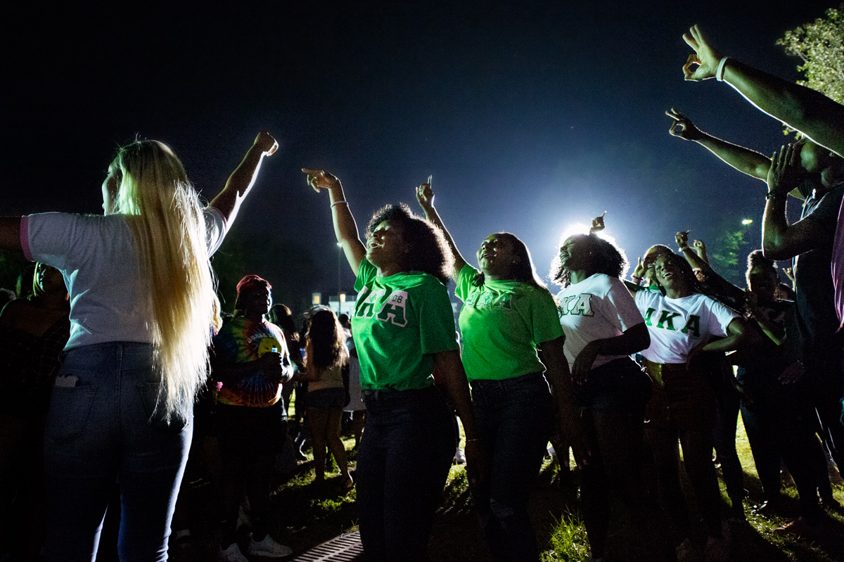 Members of Alpha Kappa Alpha sorority stroll off amongst an enthusiastic nighttime crowd at the Amphitheater.