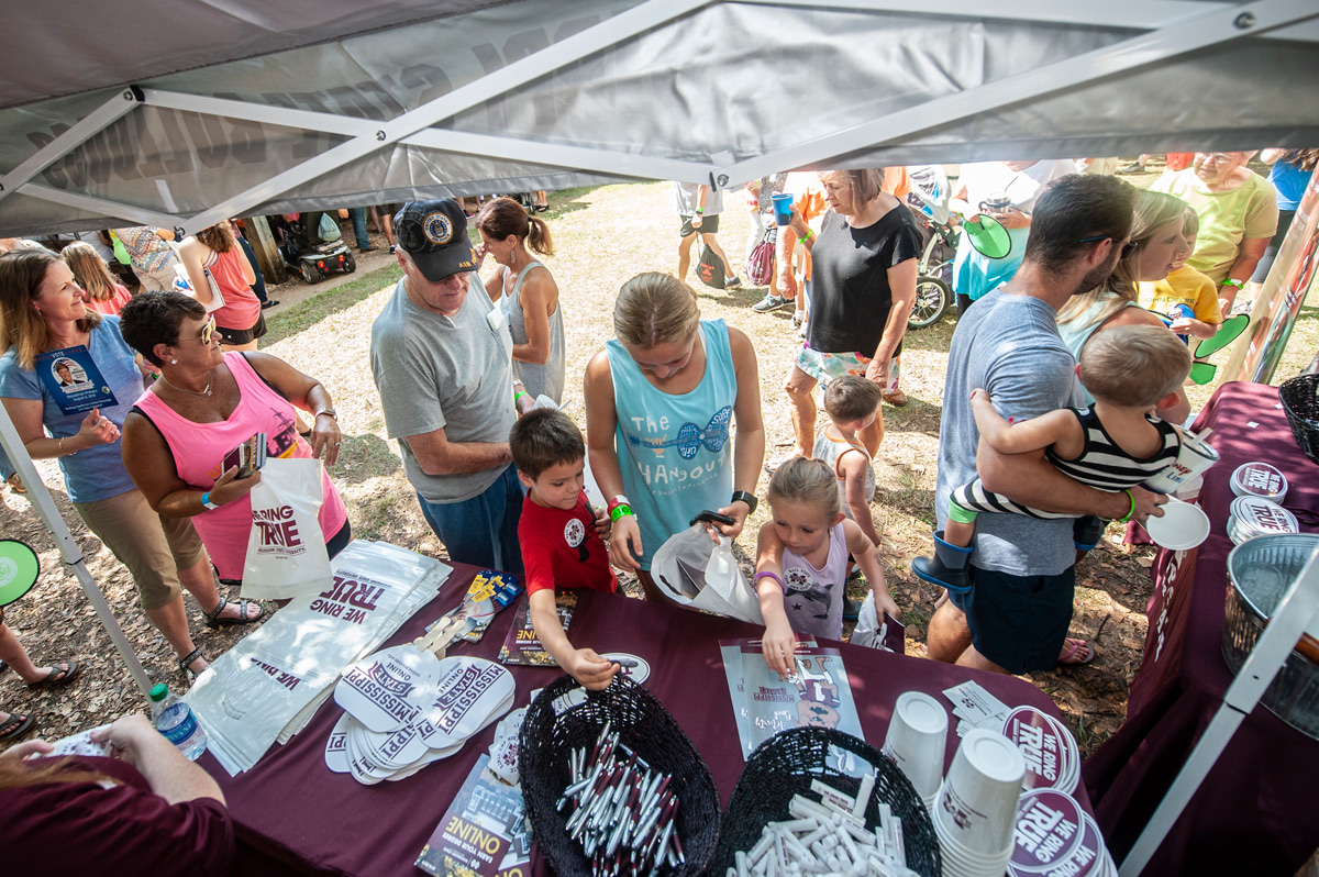 Neshoba County Fair participants gather MSU merchandise from a giveaway tent at the Neshoba County Fair.