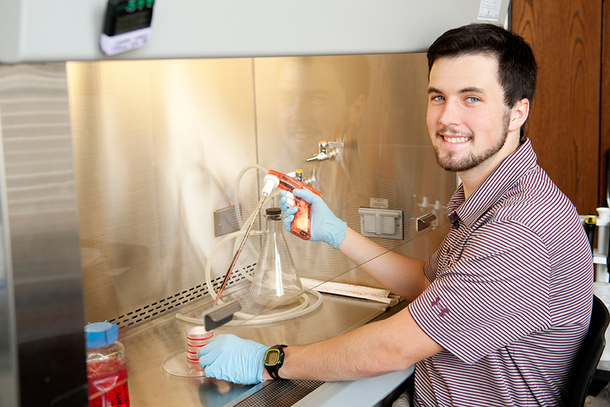 Ben Rushing in a chemical lab wearing blue safety gloves.