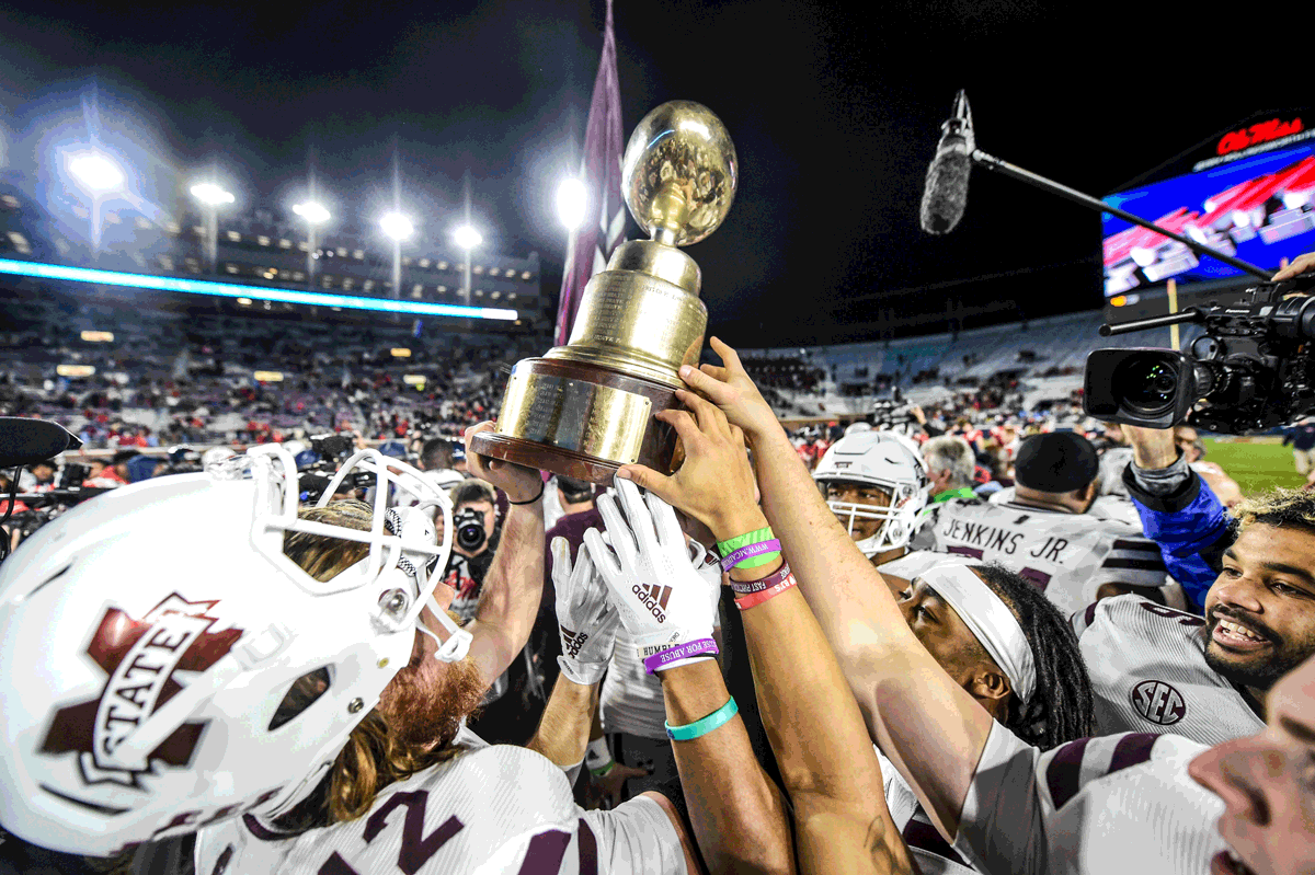 MSU players celebrate with the Egg Bowl trophy.
