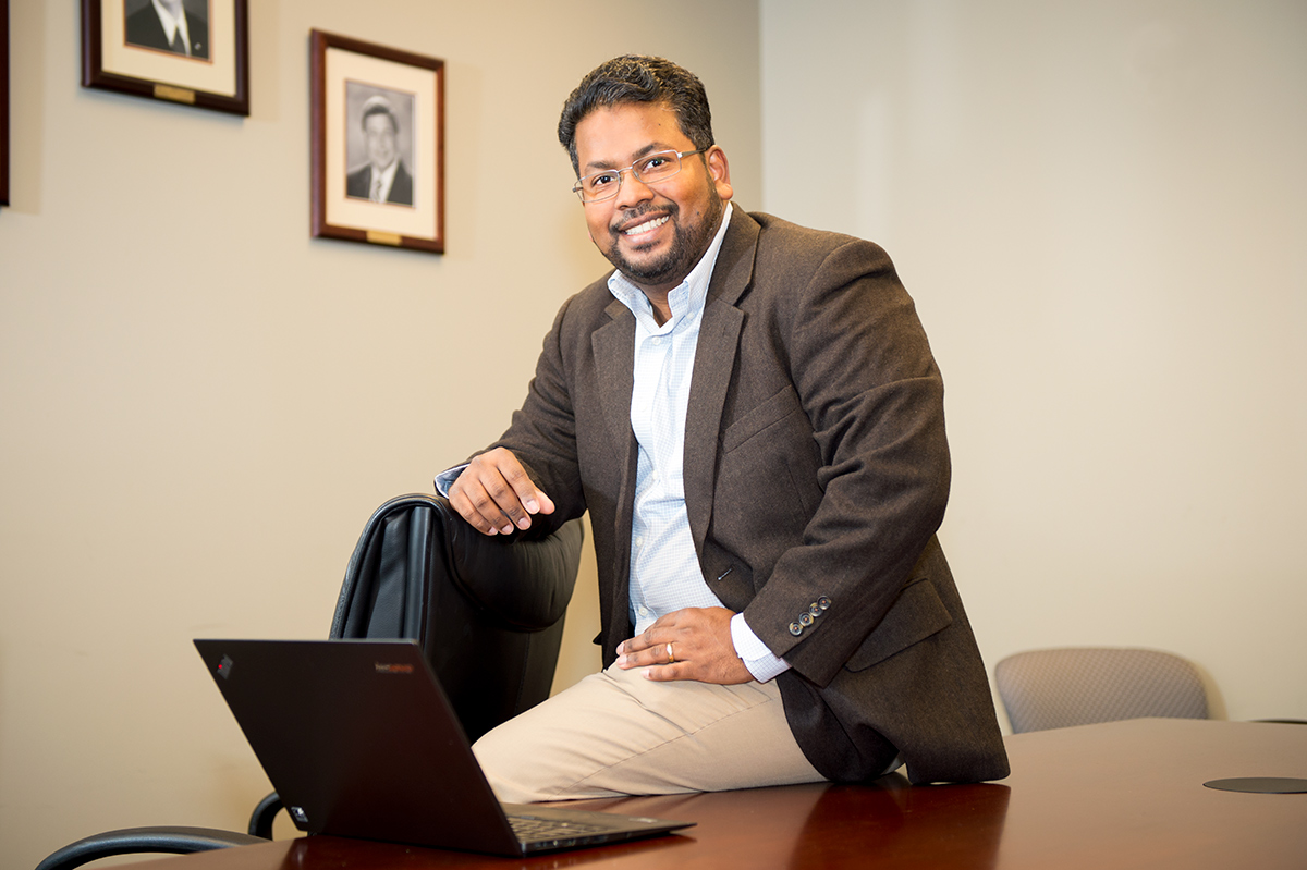 Raj Prabhu, pictured sitting on a conference room table. 