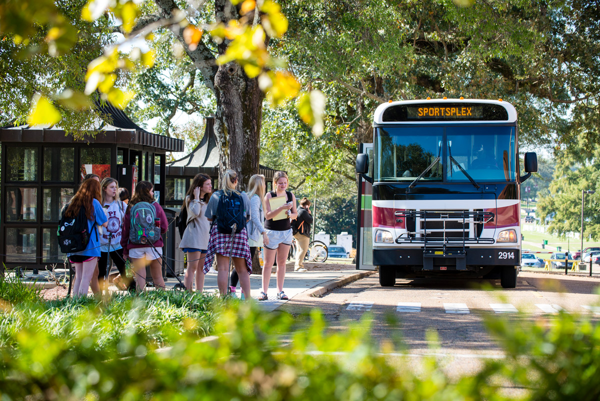 A group of female students wait at Montgomery Hall&amp;#039;s bus stop as the shuttle arrives.