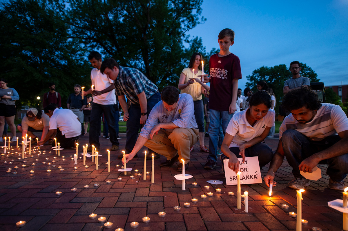 Attendees of the candlelight vigil pay their respects by placing their candles together.