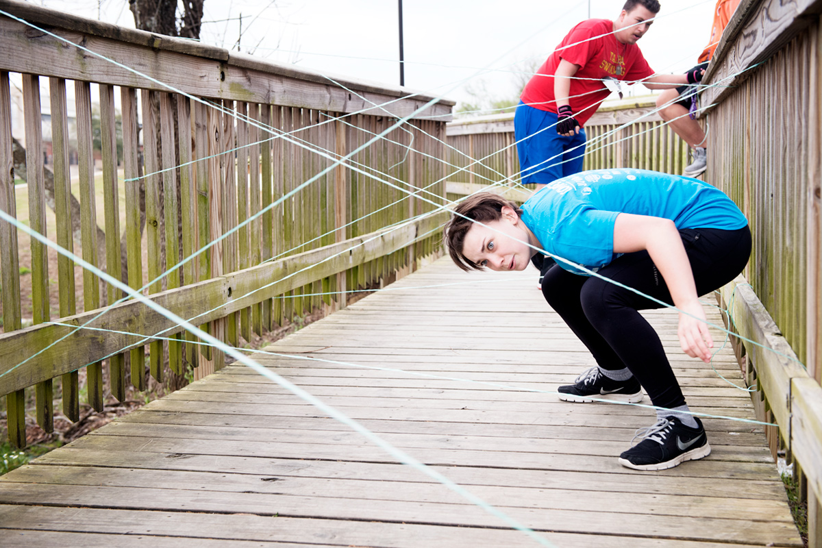 Female student in blue shirt navigating her way through a mission impossible like web of strings.