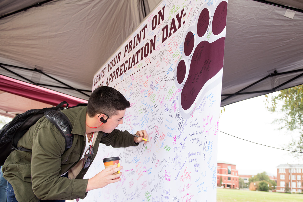 Student signing banner to thank donors for all they do.