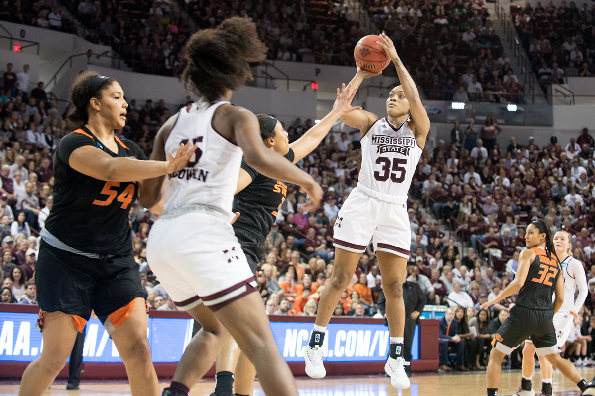MSU women&amp;#039;s basketball player in all white with maroon accents shooting the ball in Humphrey Coliseum